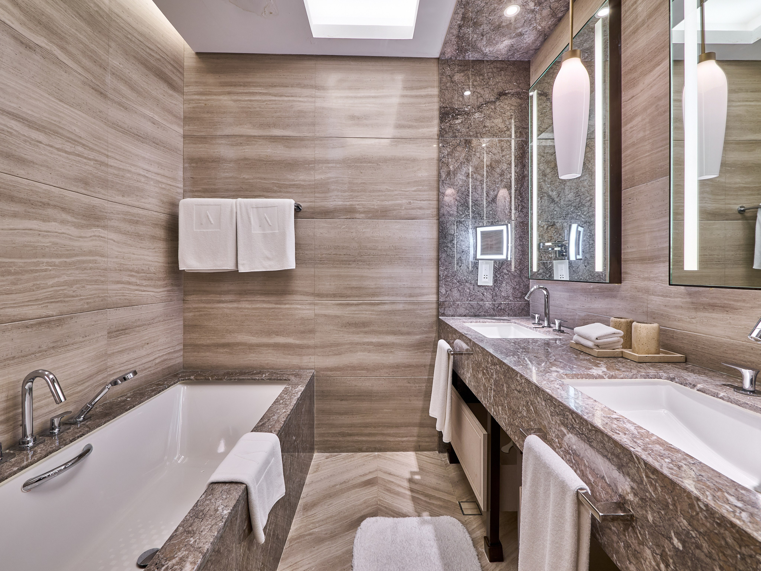 Modern hotel bathroom with double sink, large mirrors and bathtub — high-end interior photography for real estate and rental platforms.