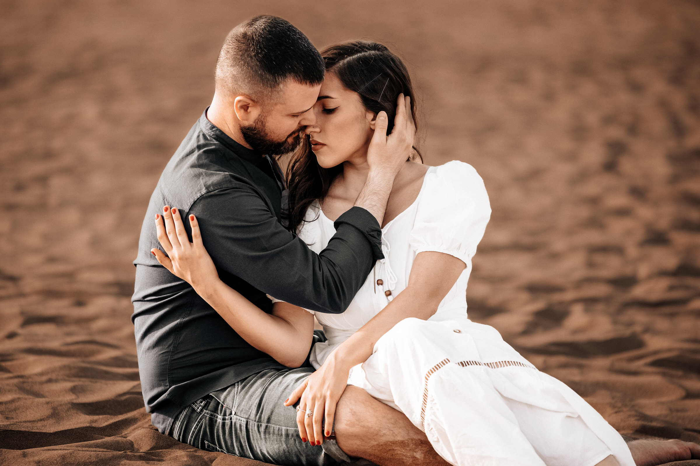 Expert Love Story Photographer in Maspalomas A couple embraced in the sand during their engagement session.