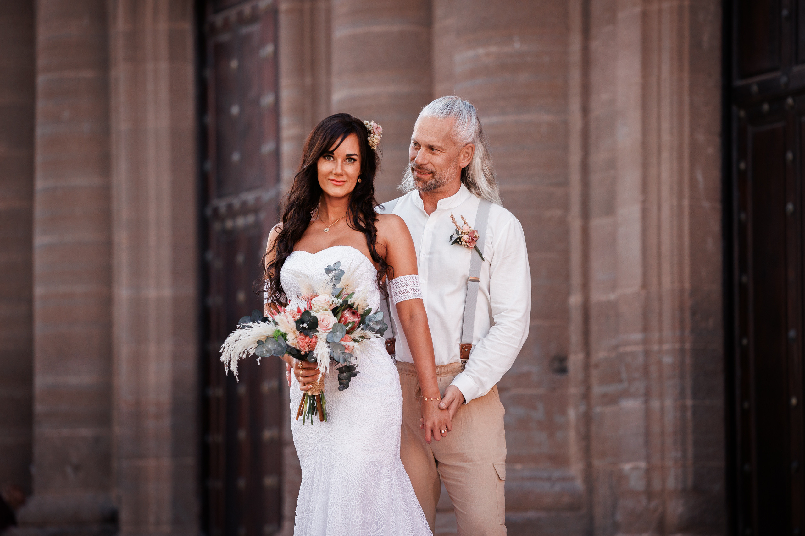 A bride and groom are standing in front of a building.