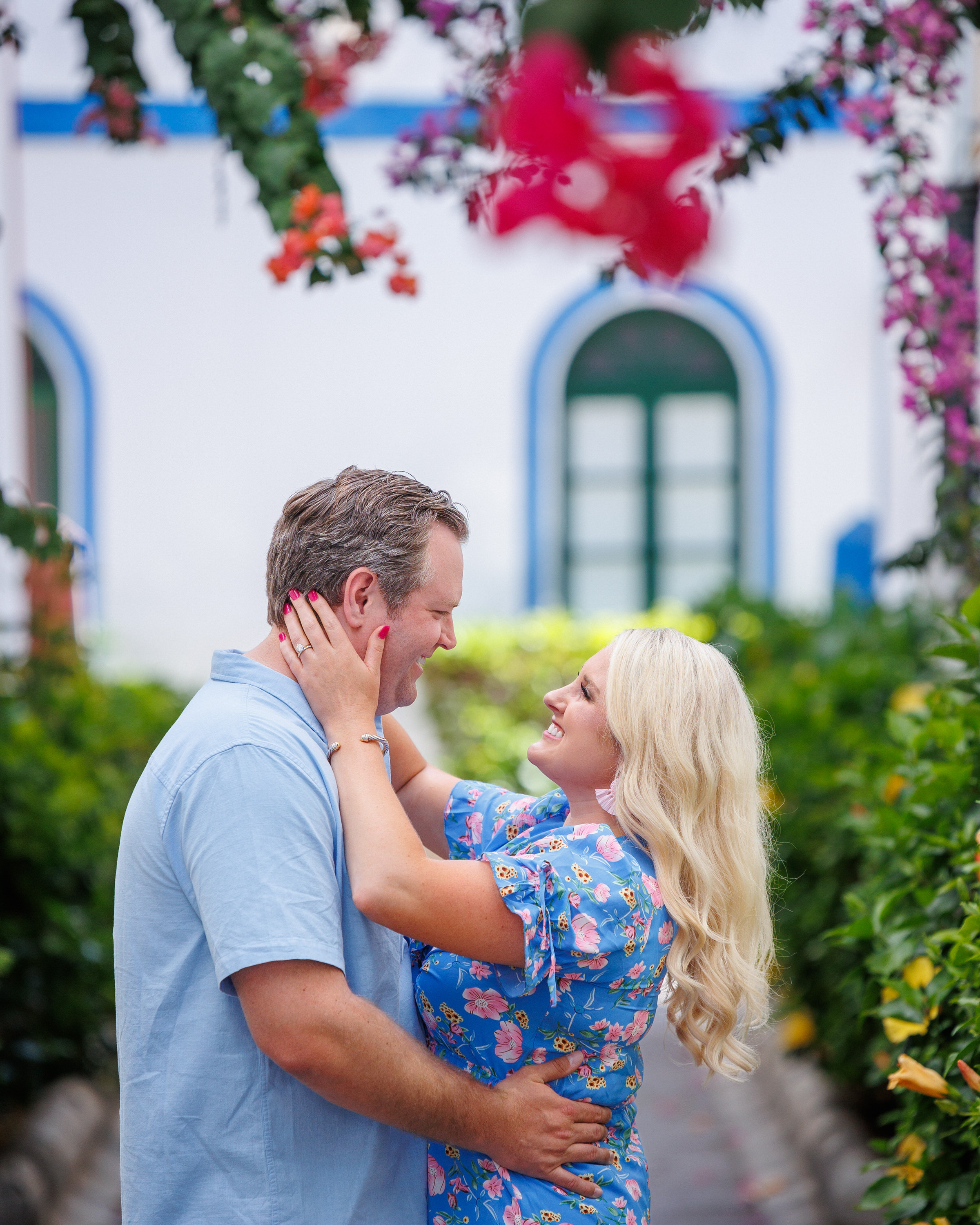 A couple embraces in front of a flower garden. Puerto de Mogan, Gran Canaria