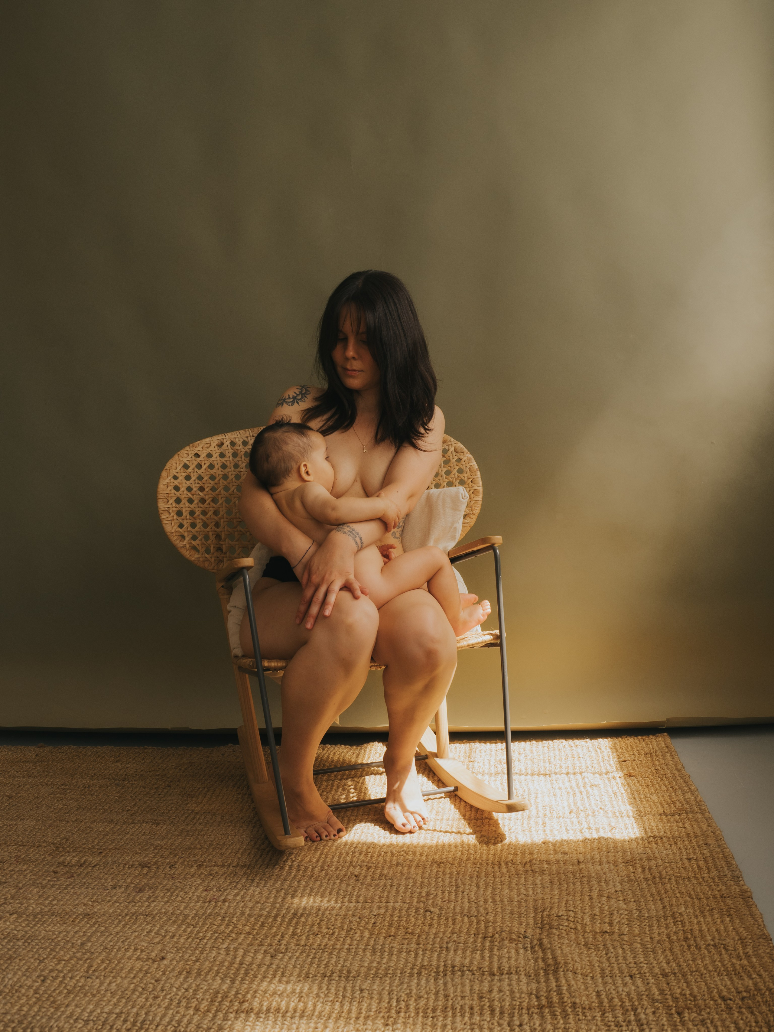 Breastfeeding Photosession showing a mother holding a child and nursing in studio.