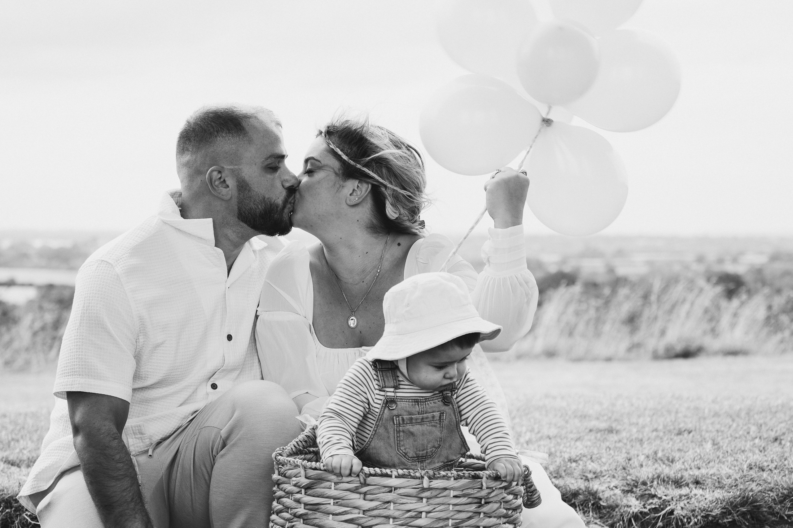 Black and white family portrait with parents and child sharing a quiet moment outdoors