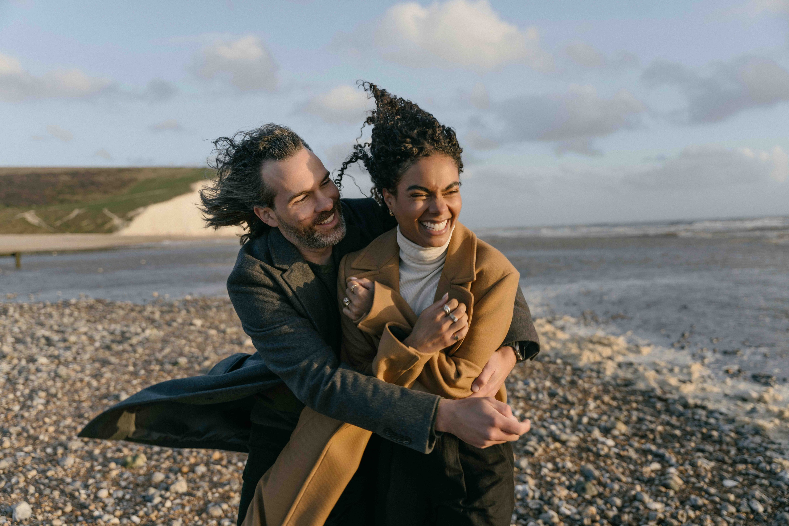 windswept couple walking seven sisters cliffs england photoshoot
