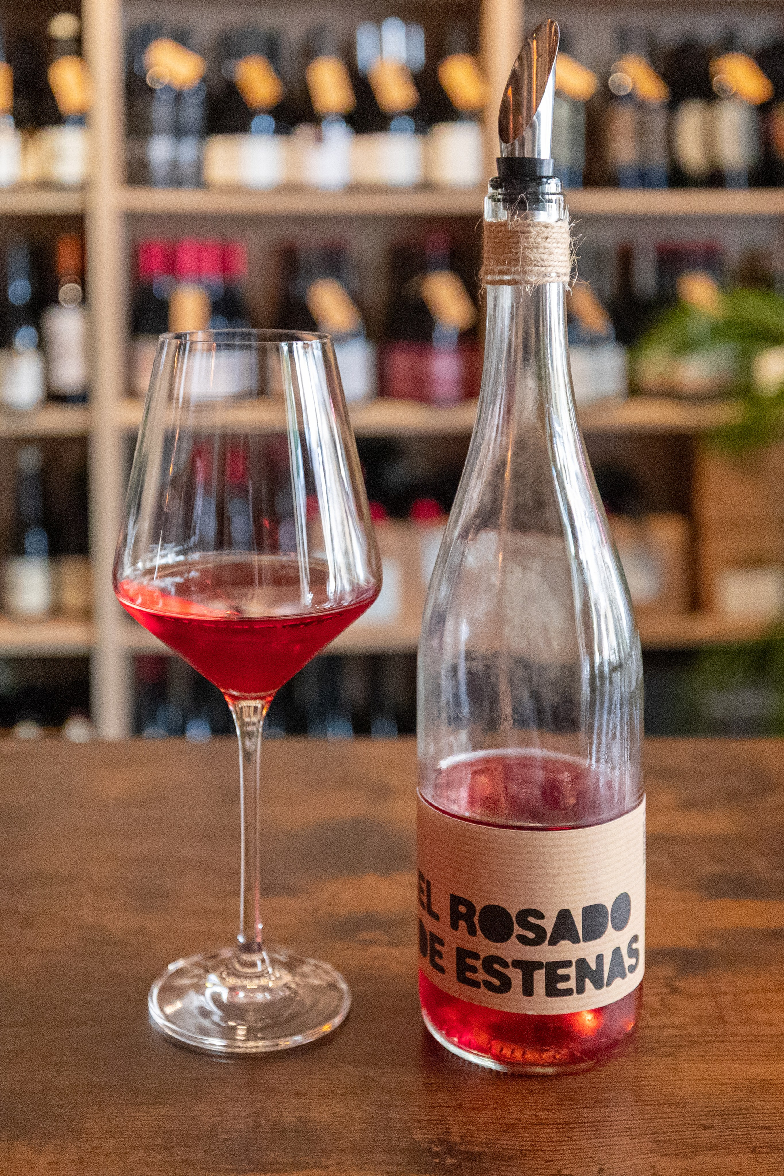 vino rosado en copa con botella en fondo de bar
