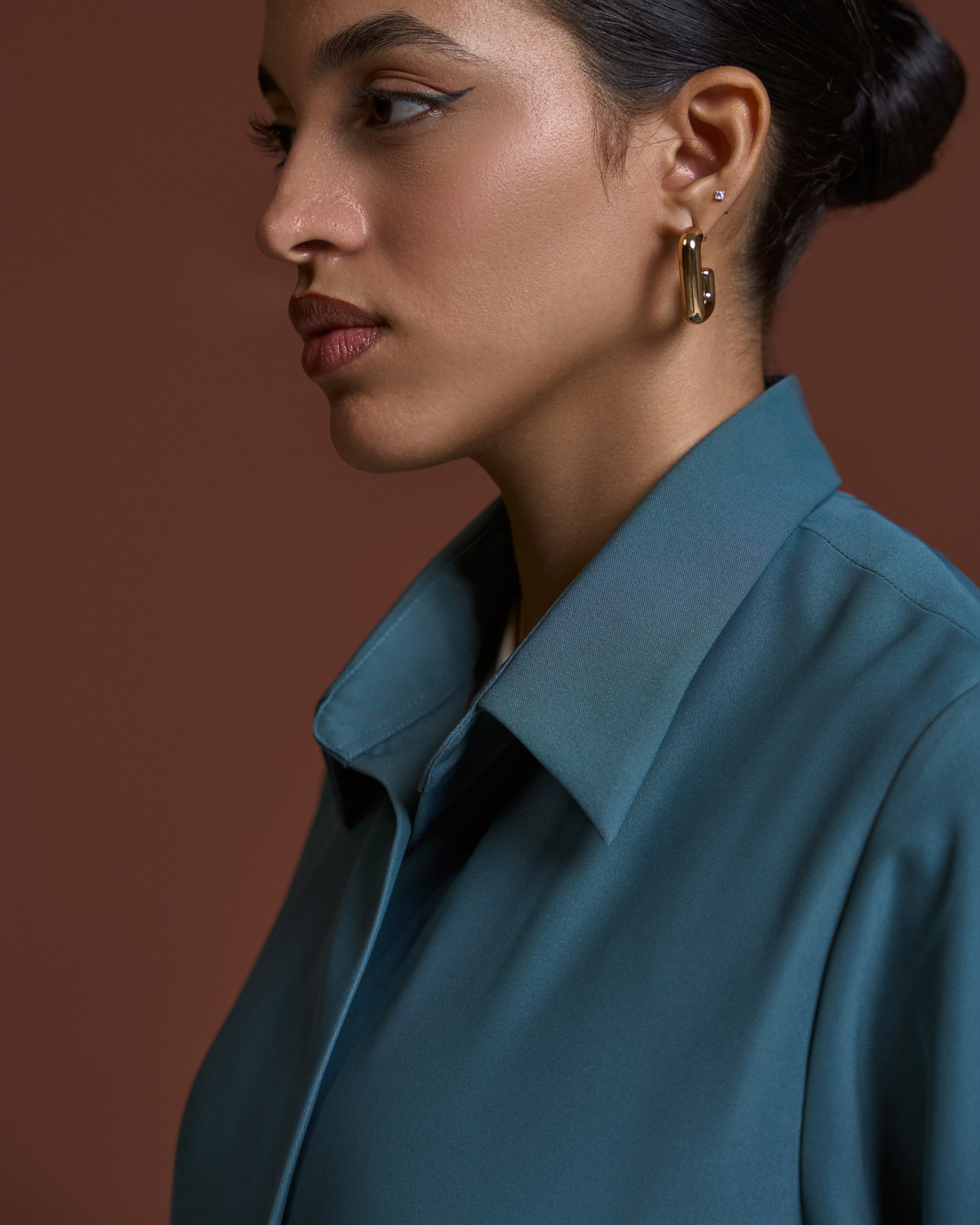 Side-profile beauty shot showcasing elegant earrings and minimal makeup