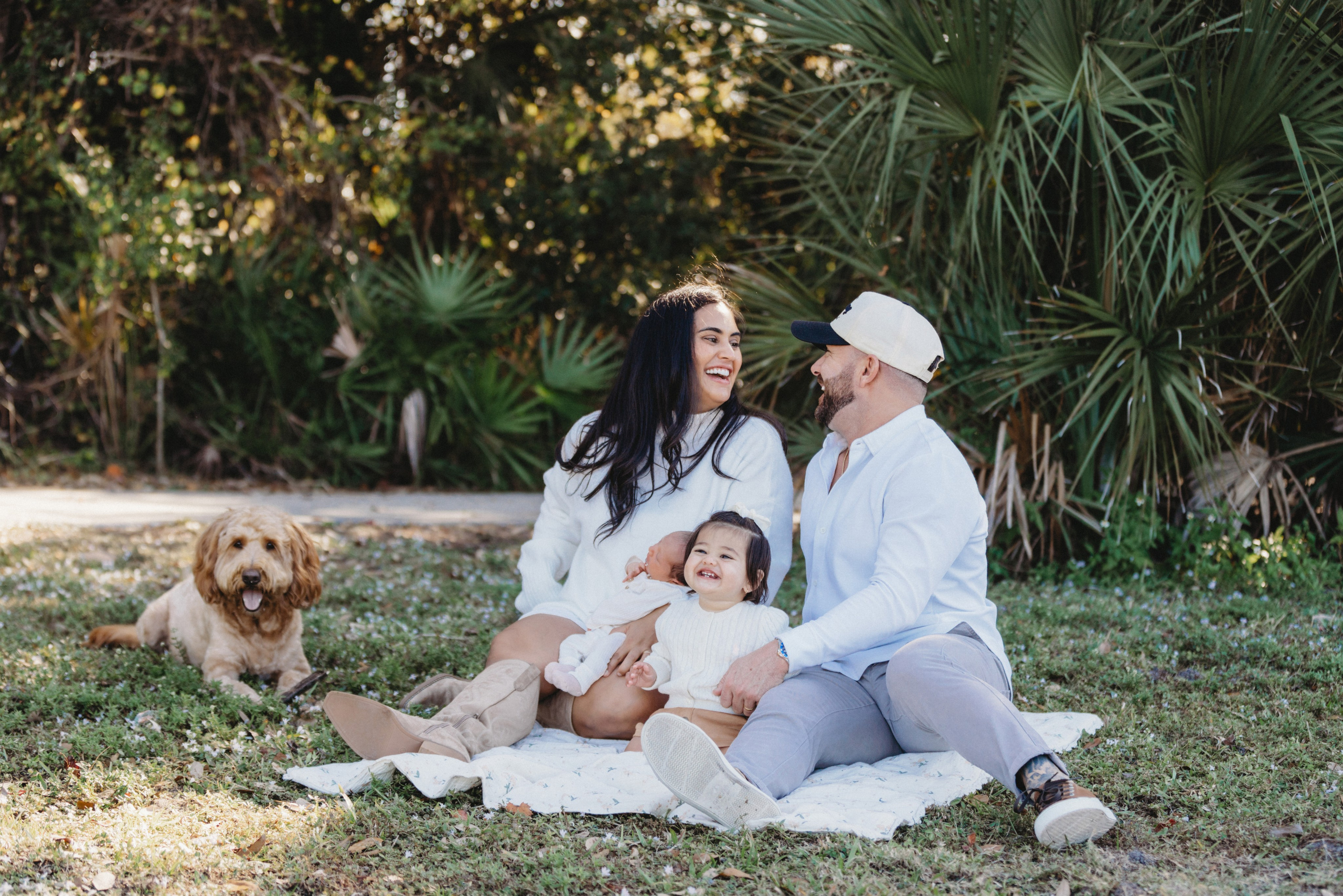 Young family sitting on the blanket with the dog