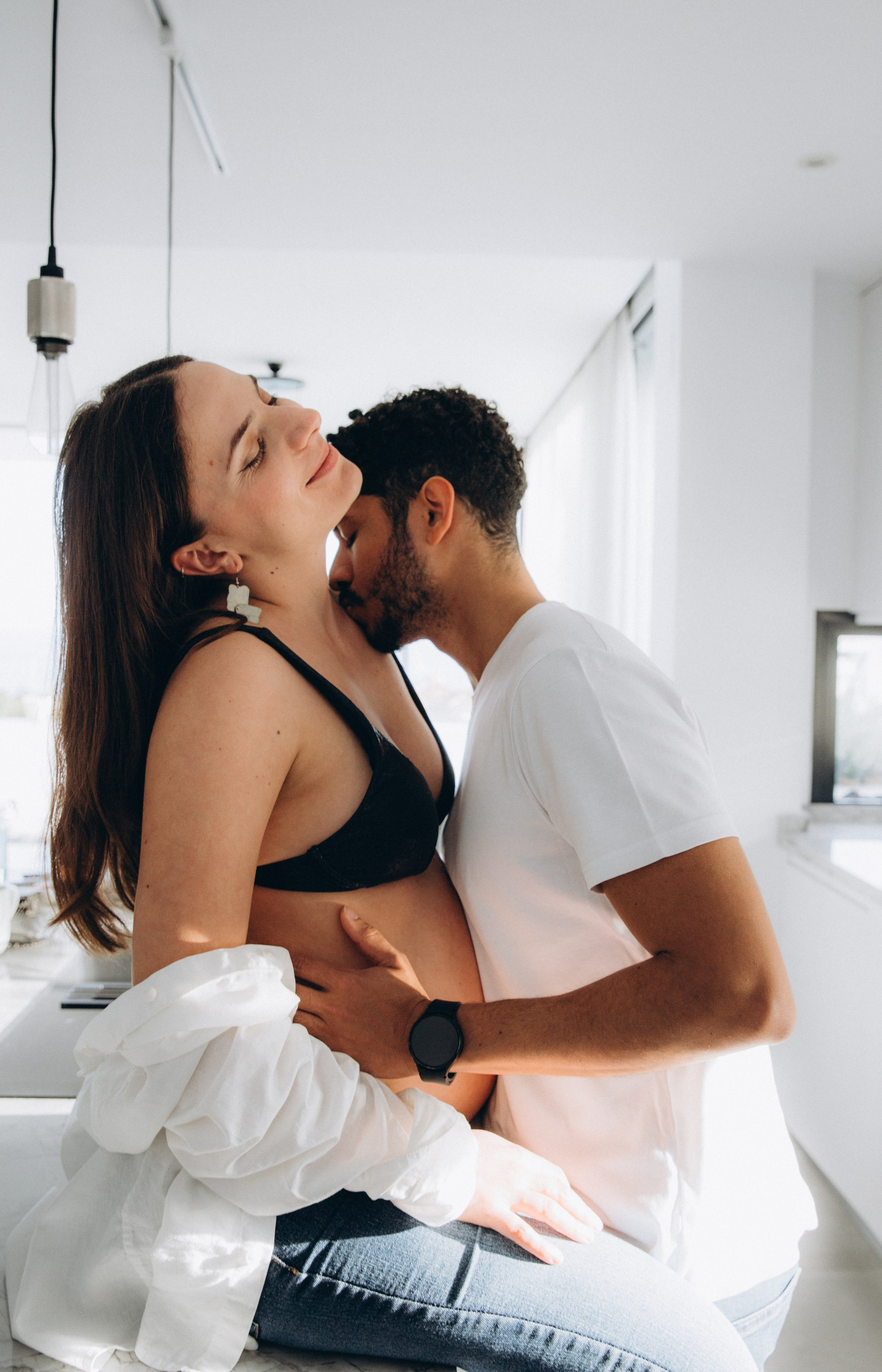 Sesión íntima de embarazo en interior en Madrid, España — momento romántico entre pareja embarazada en un entorno minimalista moderno. Ideal para quienes buscan fotografía artística y emocional en Madrid y toda España.