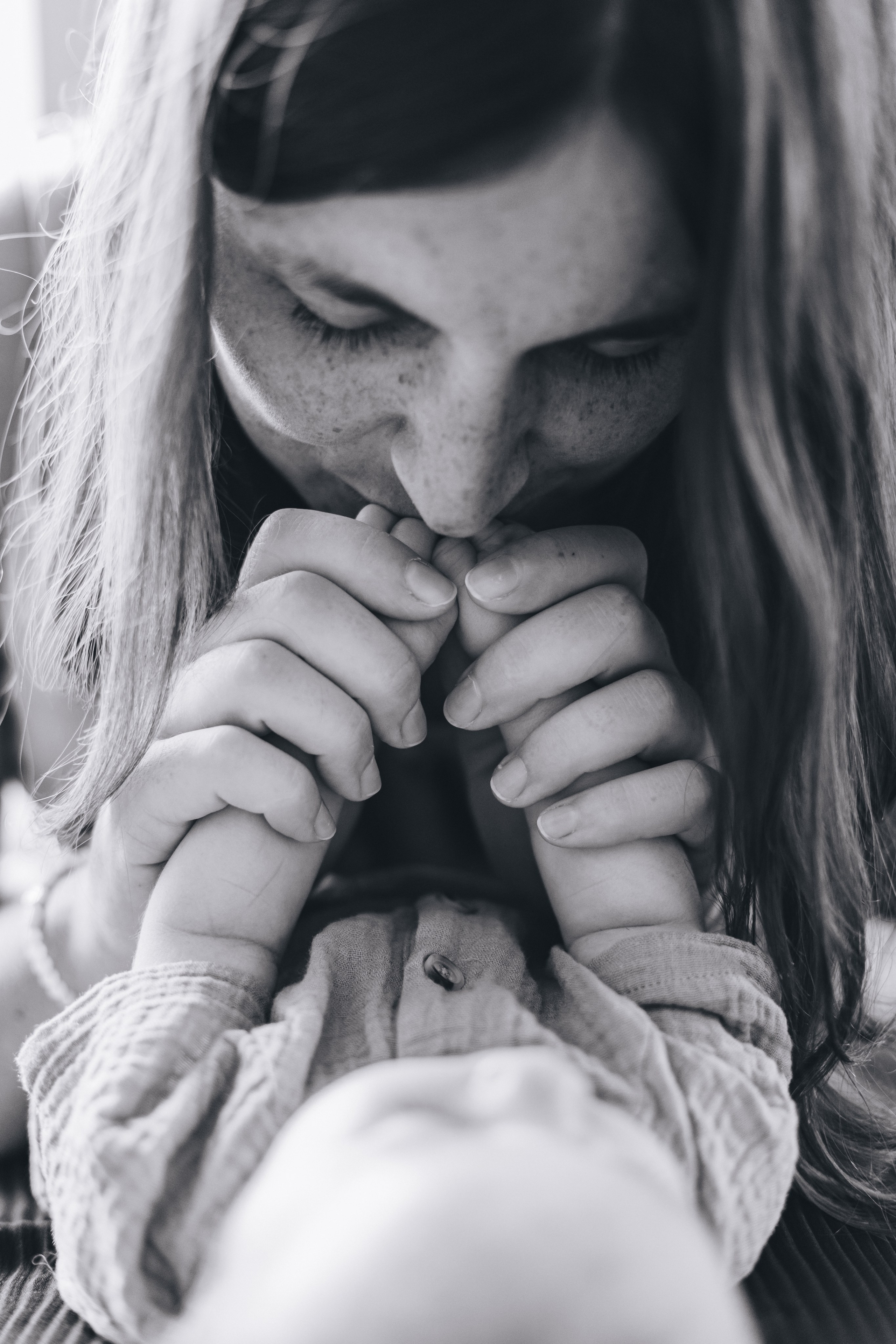 Mutter küsst die kleinen Hände ihrer Tochter.