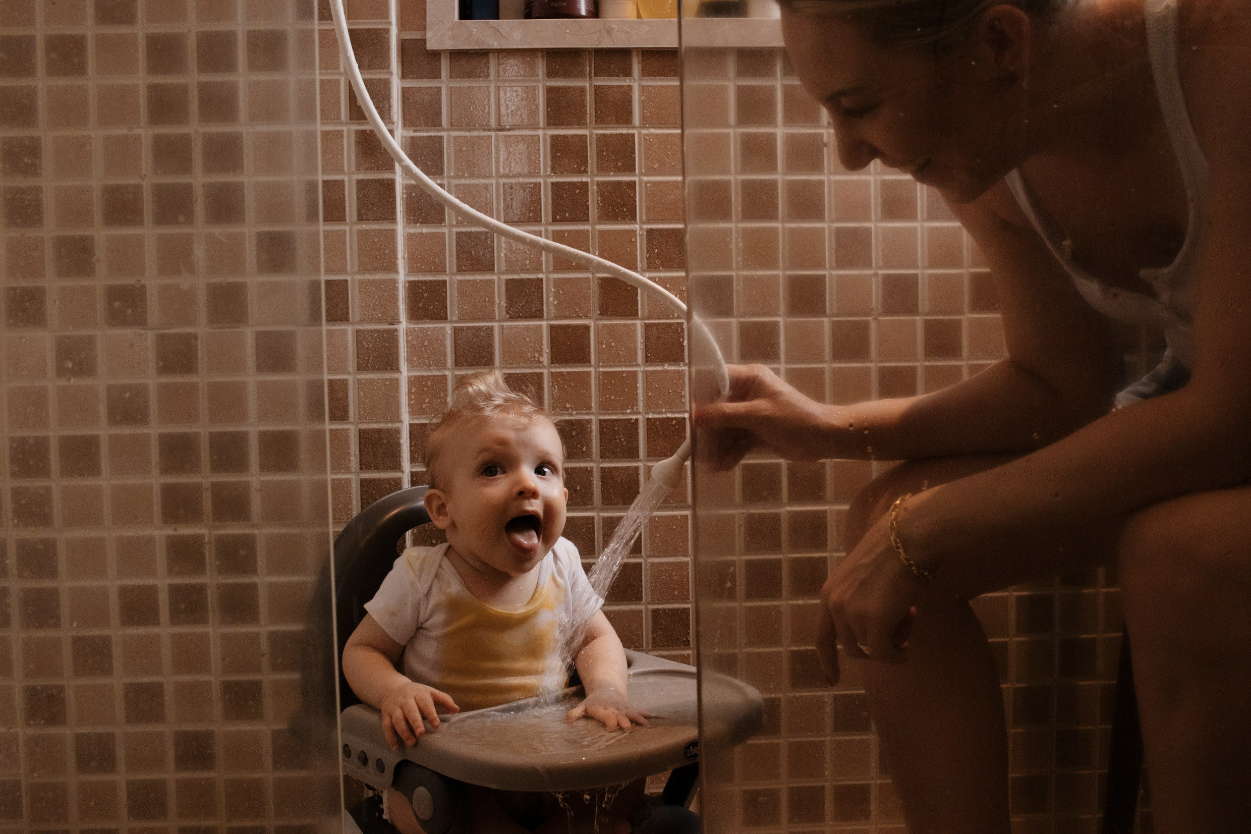 Mãe dando banho no filho em cadeira de alimentação