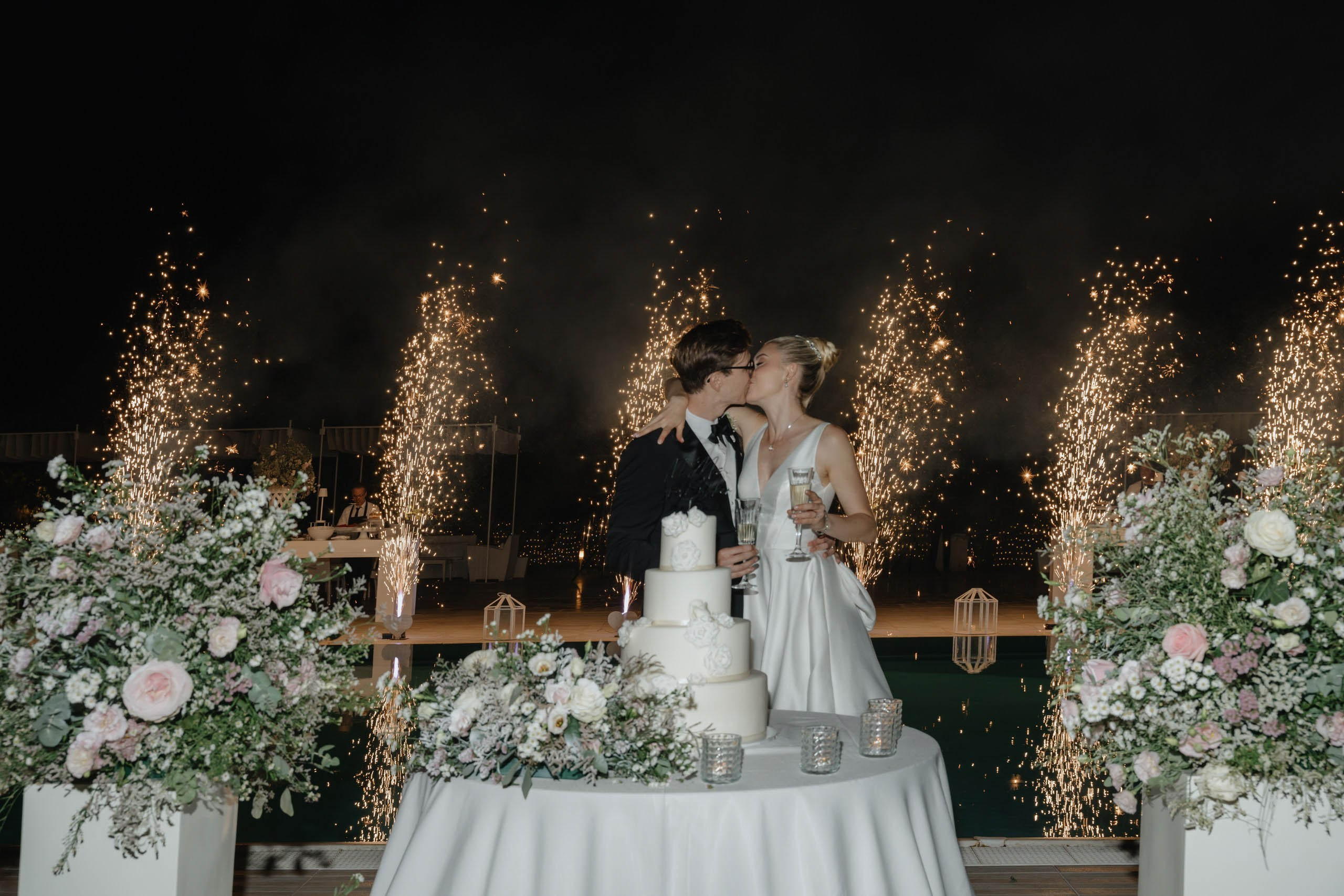 Bride and groom cutting wedding cake at night, elegant destination wedding in Ostuni Italy