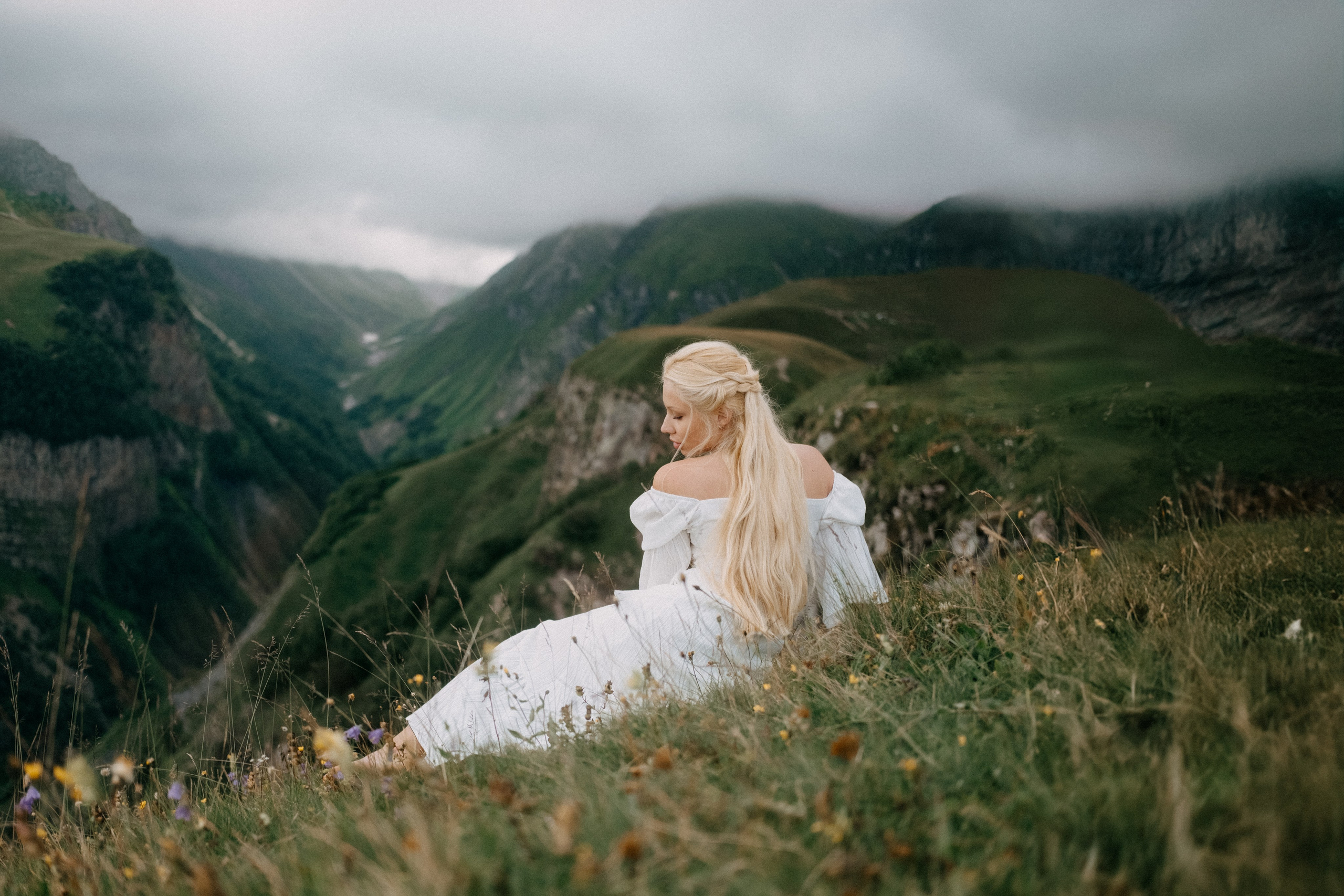 Woman sitting on hillside overlooking valley