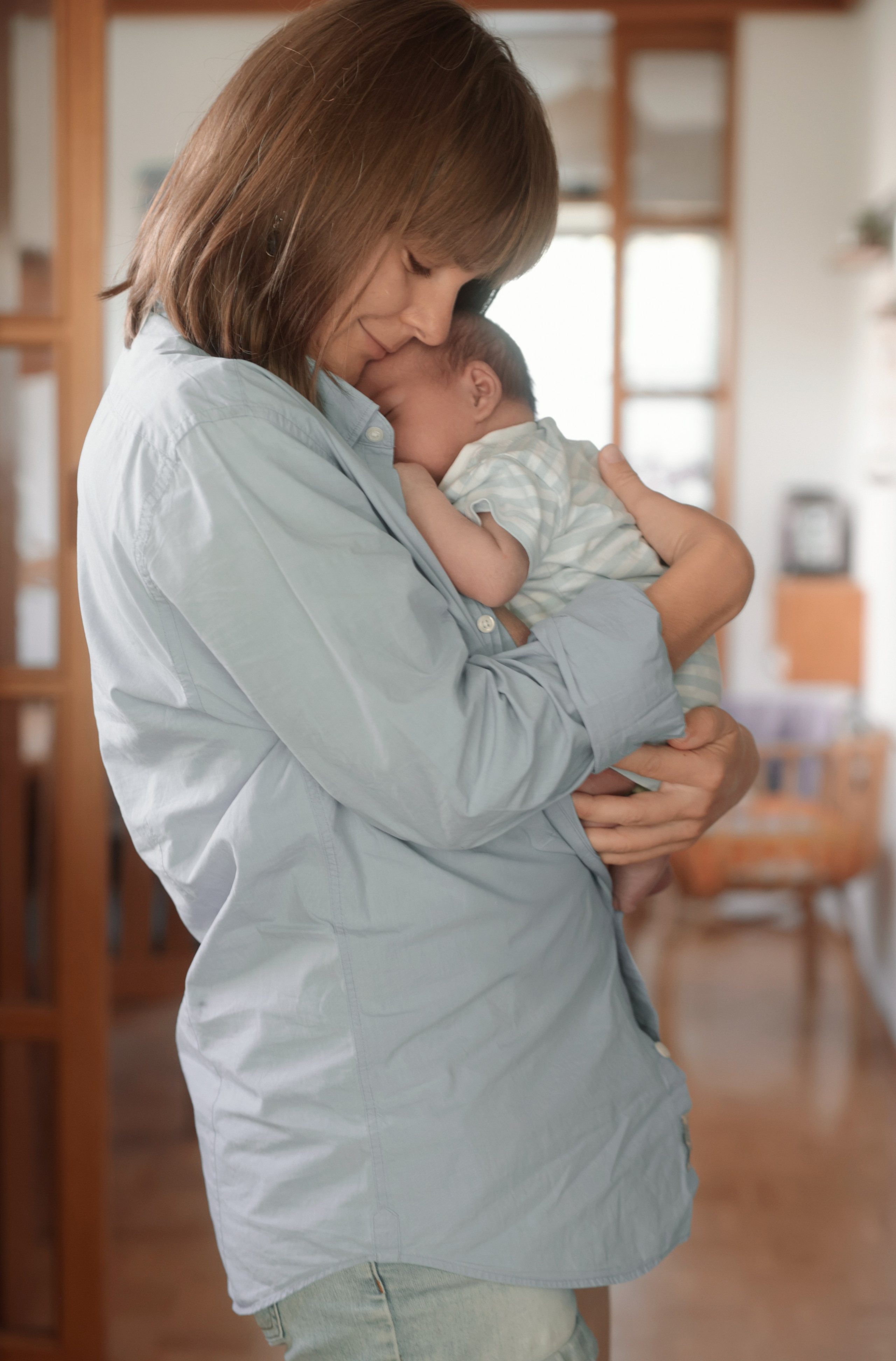 Mutter hält ihr Neugeborenes liebevoll  – zarter Moment der Bindung im natürlichen Licht bei einem Babyshooting in Salzburg 