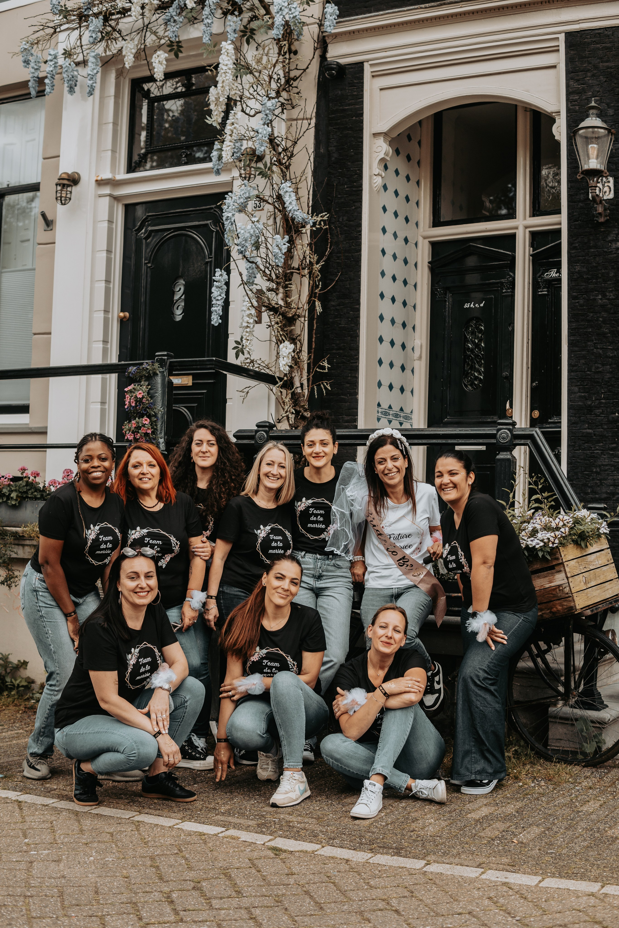 girls and bride to be standing infront of a canal house with wisteria flowers