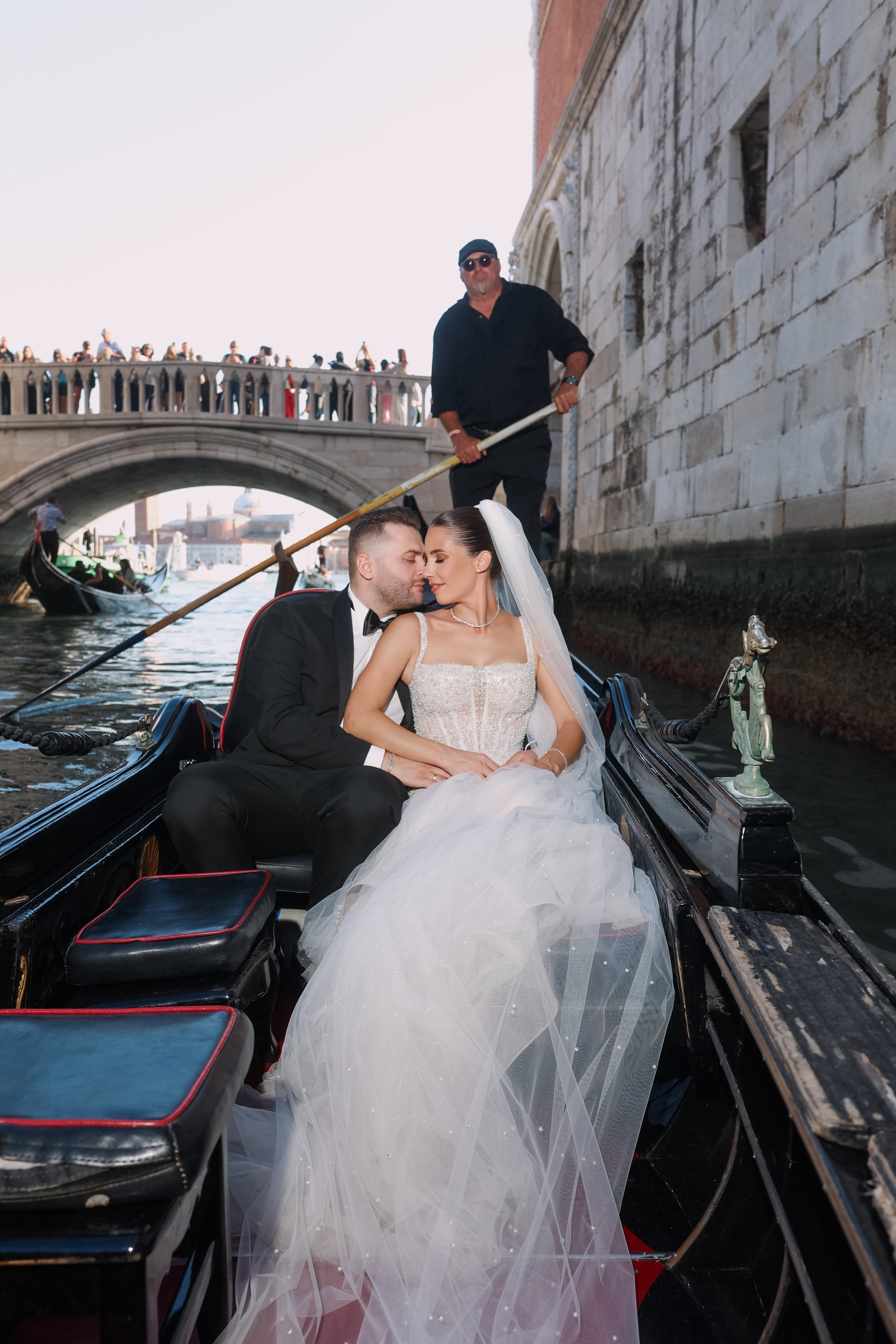 Romantic portrait of a bride and groom by a gondola docked along the Venetian canals