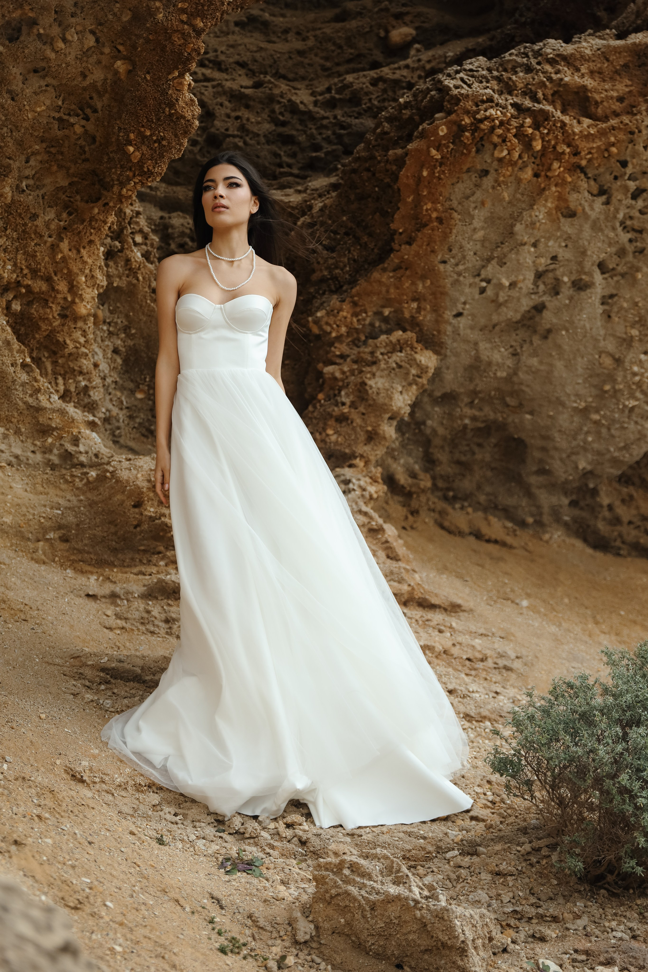 An art photo shoot of a girl in a wedding dress on the windy Kalithea beach in Rhodes, Greece
