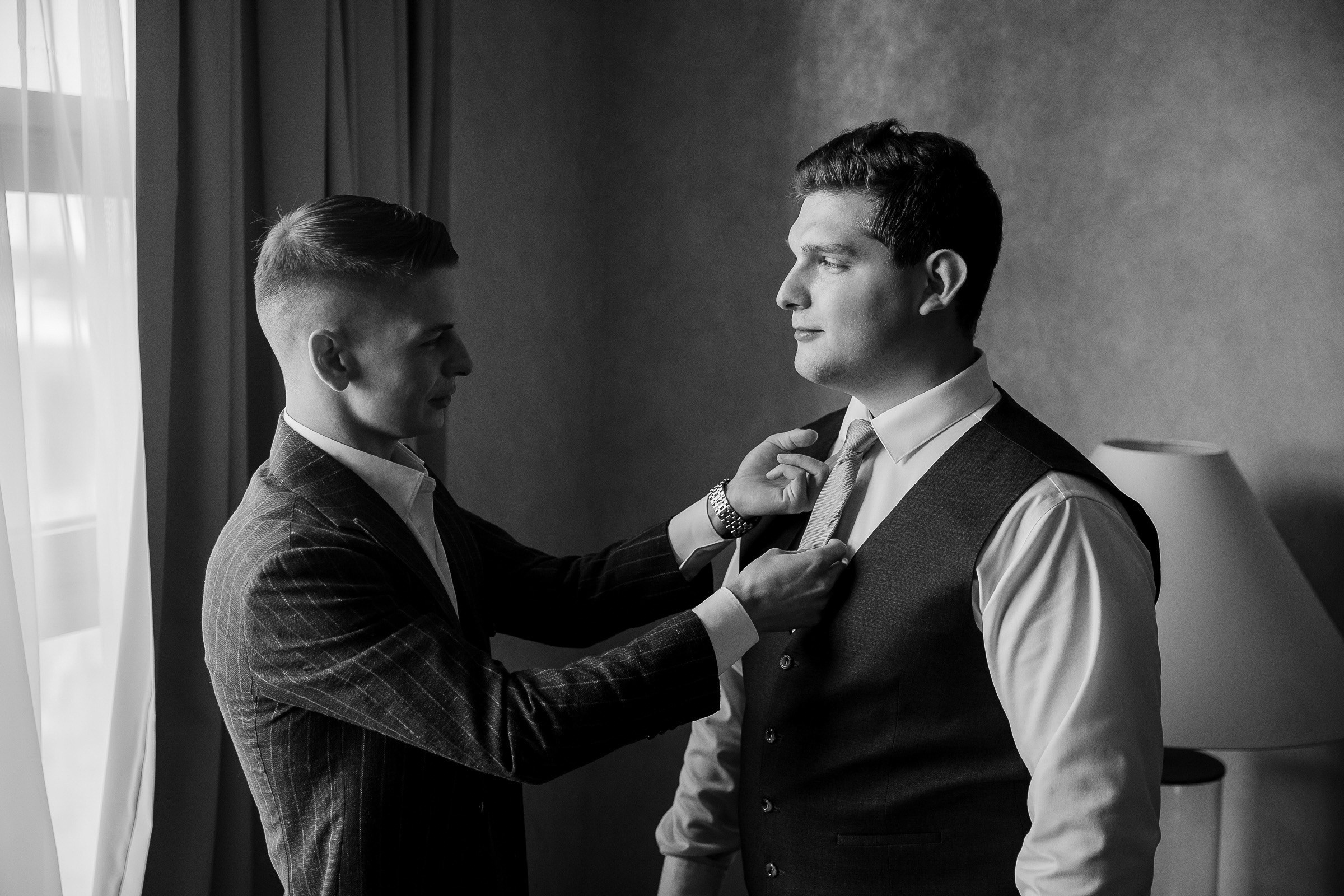 Groom adjusting tie in candid moment by Cornwall reportage wedding photographer.