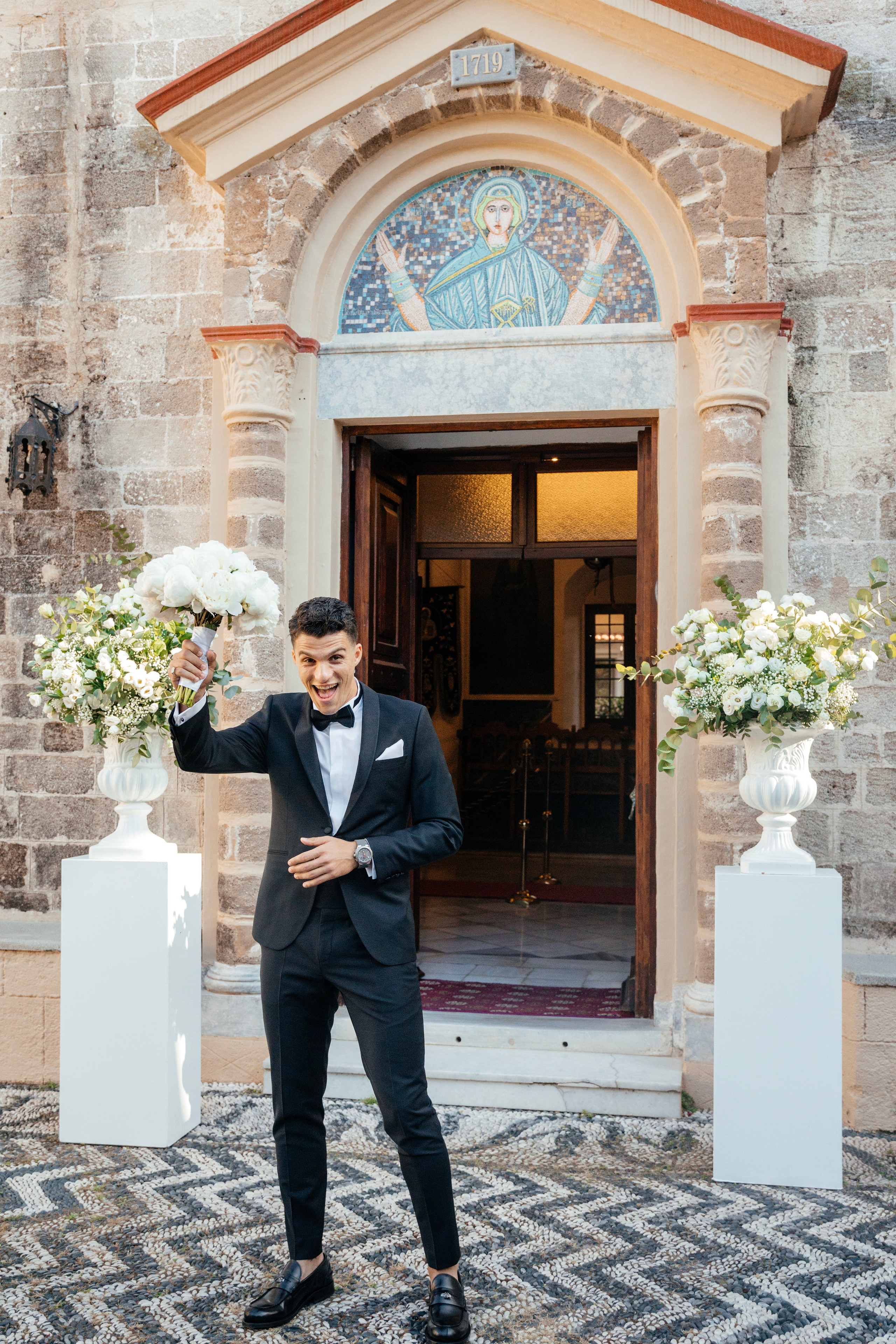 A groom is happy and waiting for the bride near the church.  Rhodes Greece