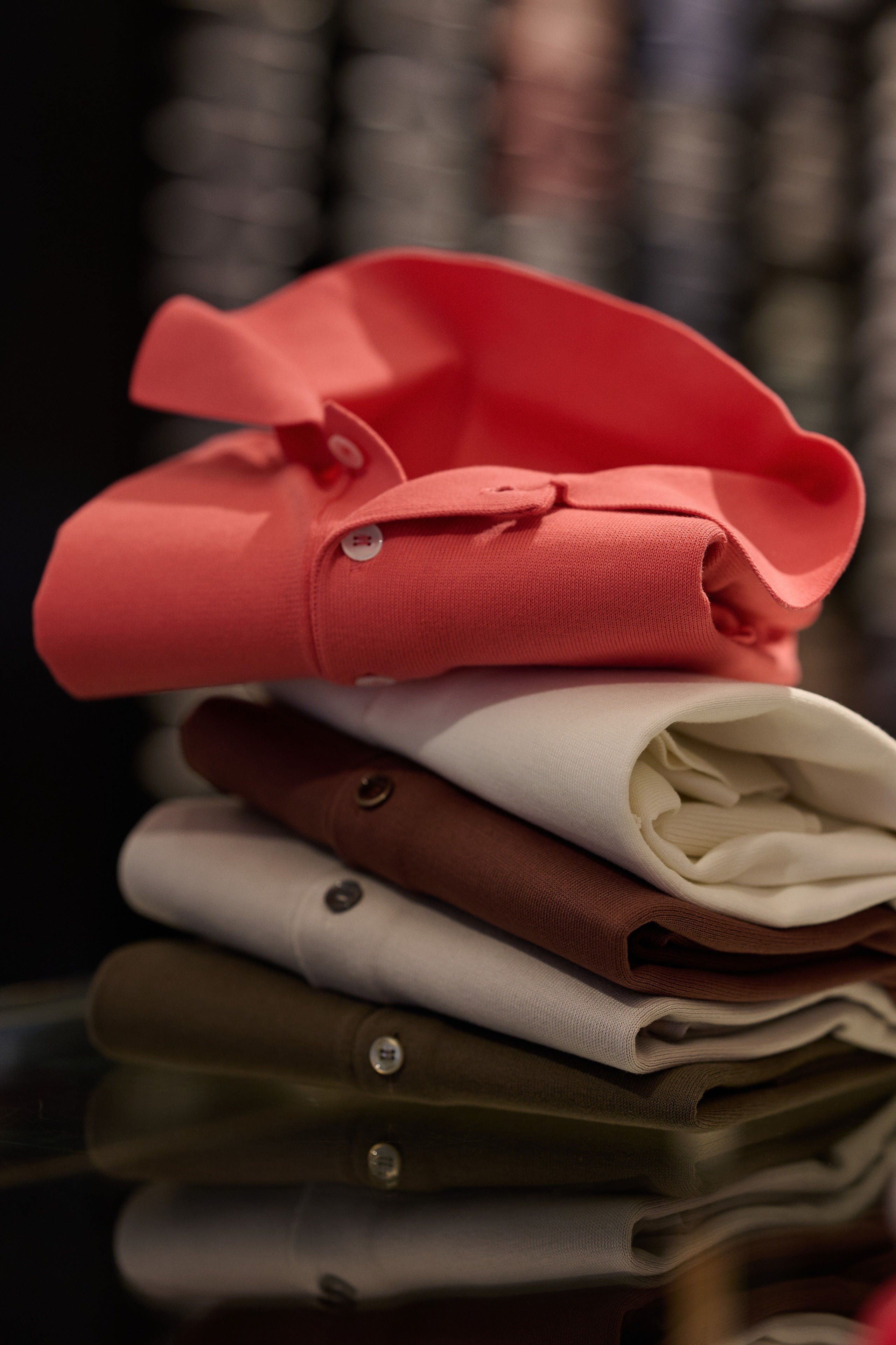 Produktfotografie Wien – Roter Wollpullover und Schal auf Stapel aus Stoffmustern.