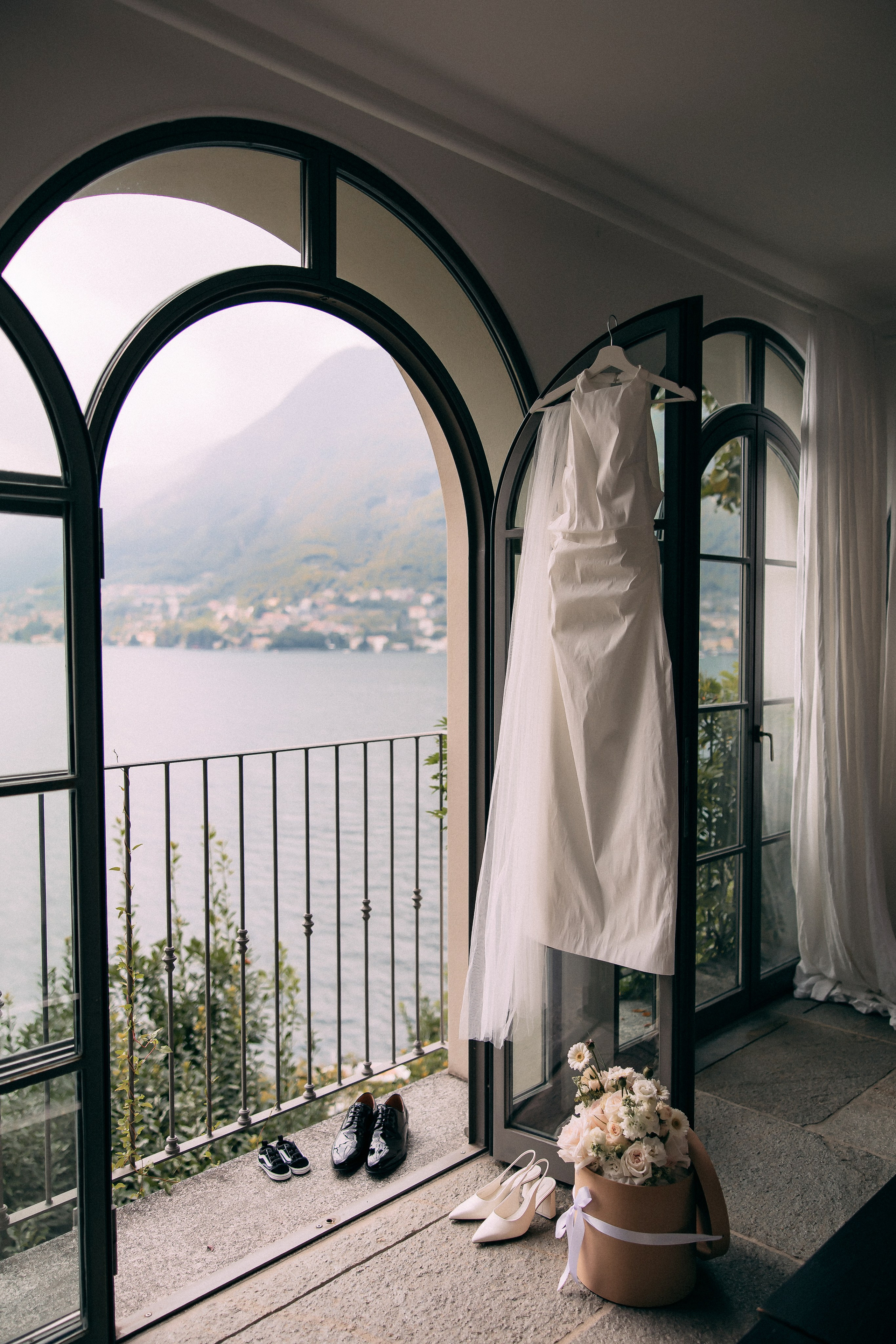 Wedding dress and teddy bear by the arched window at Villa Lario overlooking Lake Como, Italy