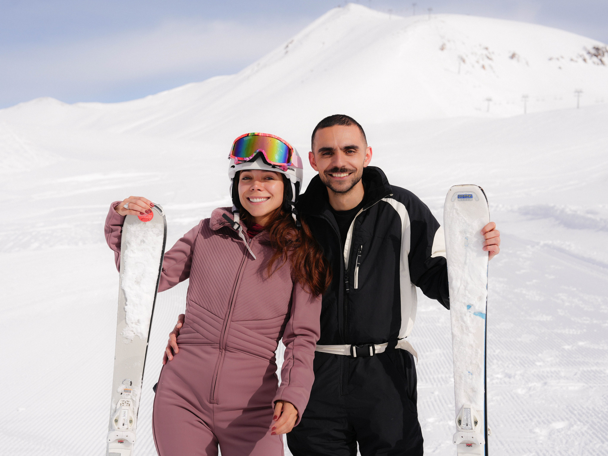 Couple with skis against snowy mountain backdrop