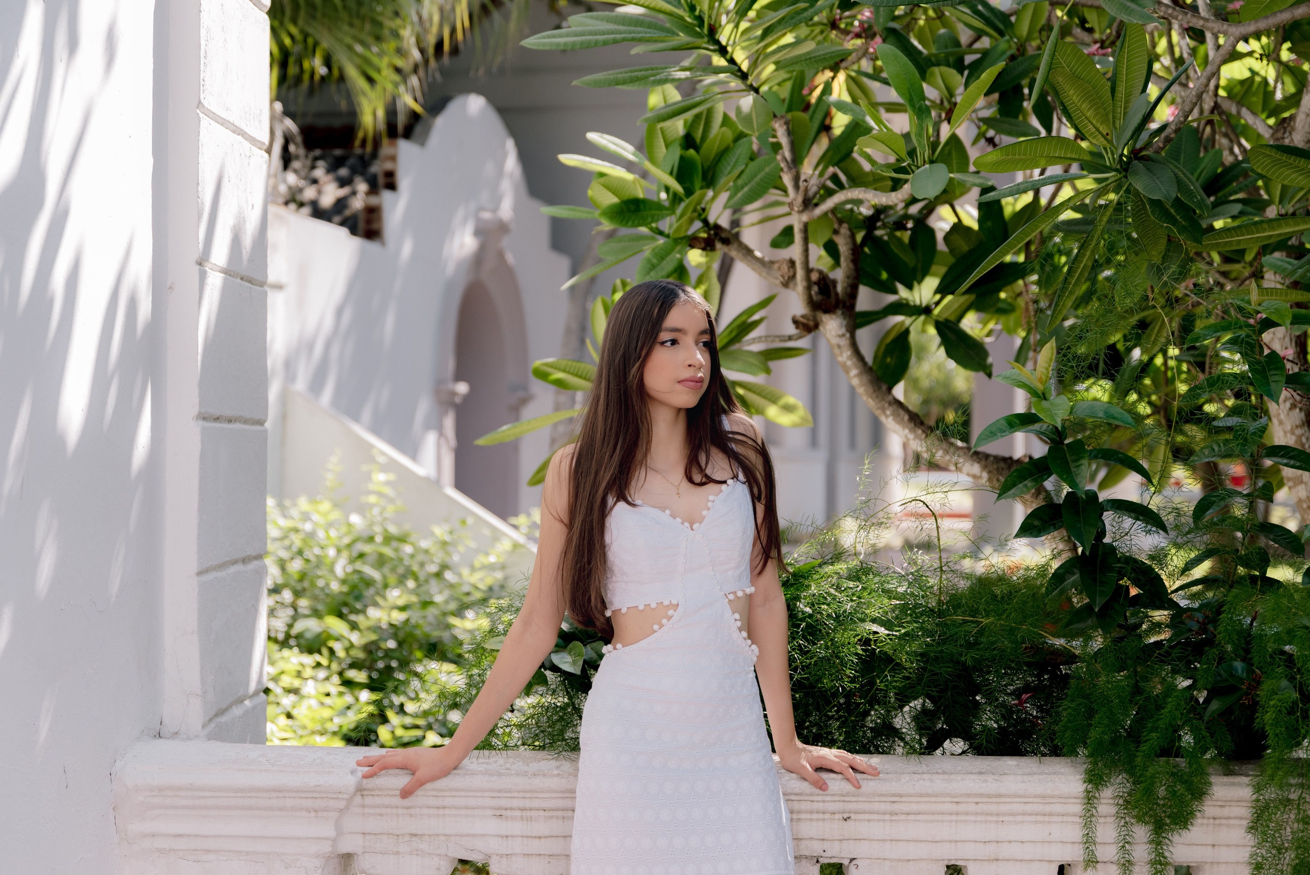 Quinceañera posando con vestido blanco en ambiente natural verde para sesión fotográfica profesional Barranquilla