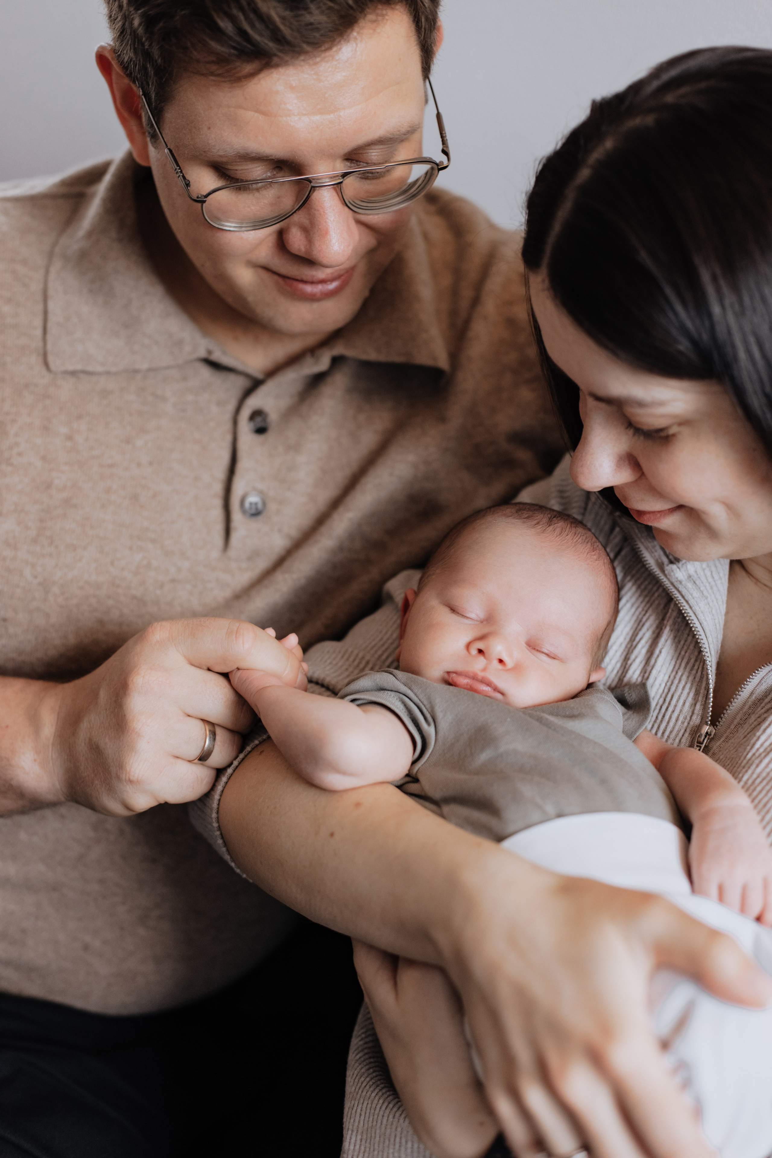 Eltern umarmen liebevoll ihren neugeborenen Sohn während der Fotosession.