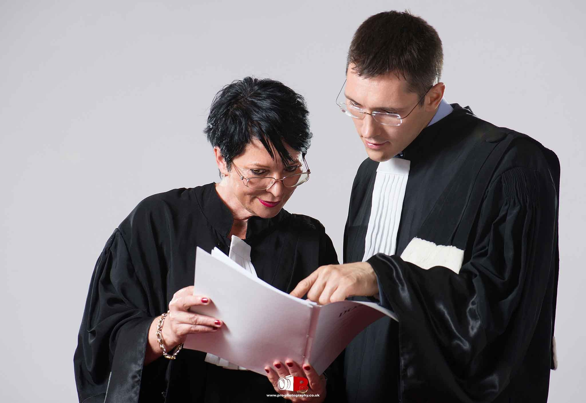 Two lawyers in formal black robes reviewing paperwork together in a professional setting.