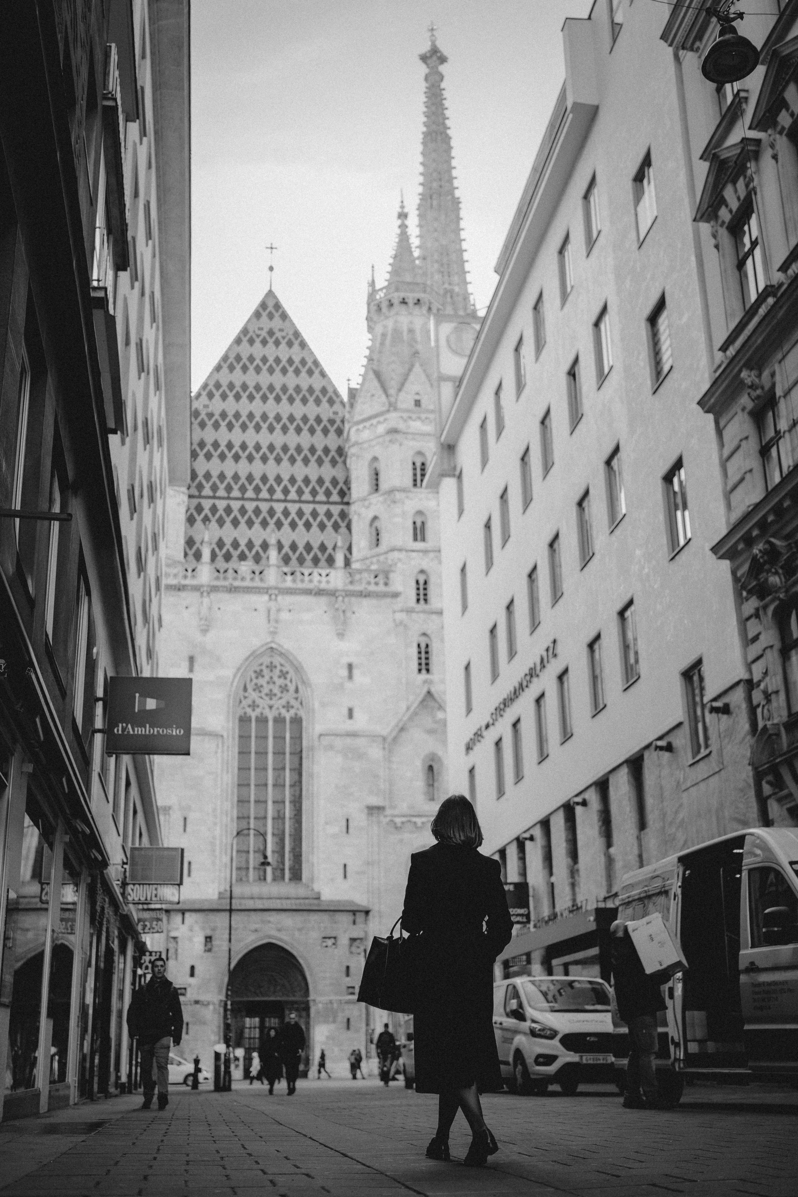 Black and white street photograph of a woman walking towards St. Stephen's Cathedral in Vienna