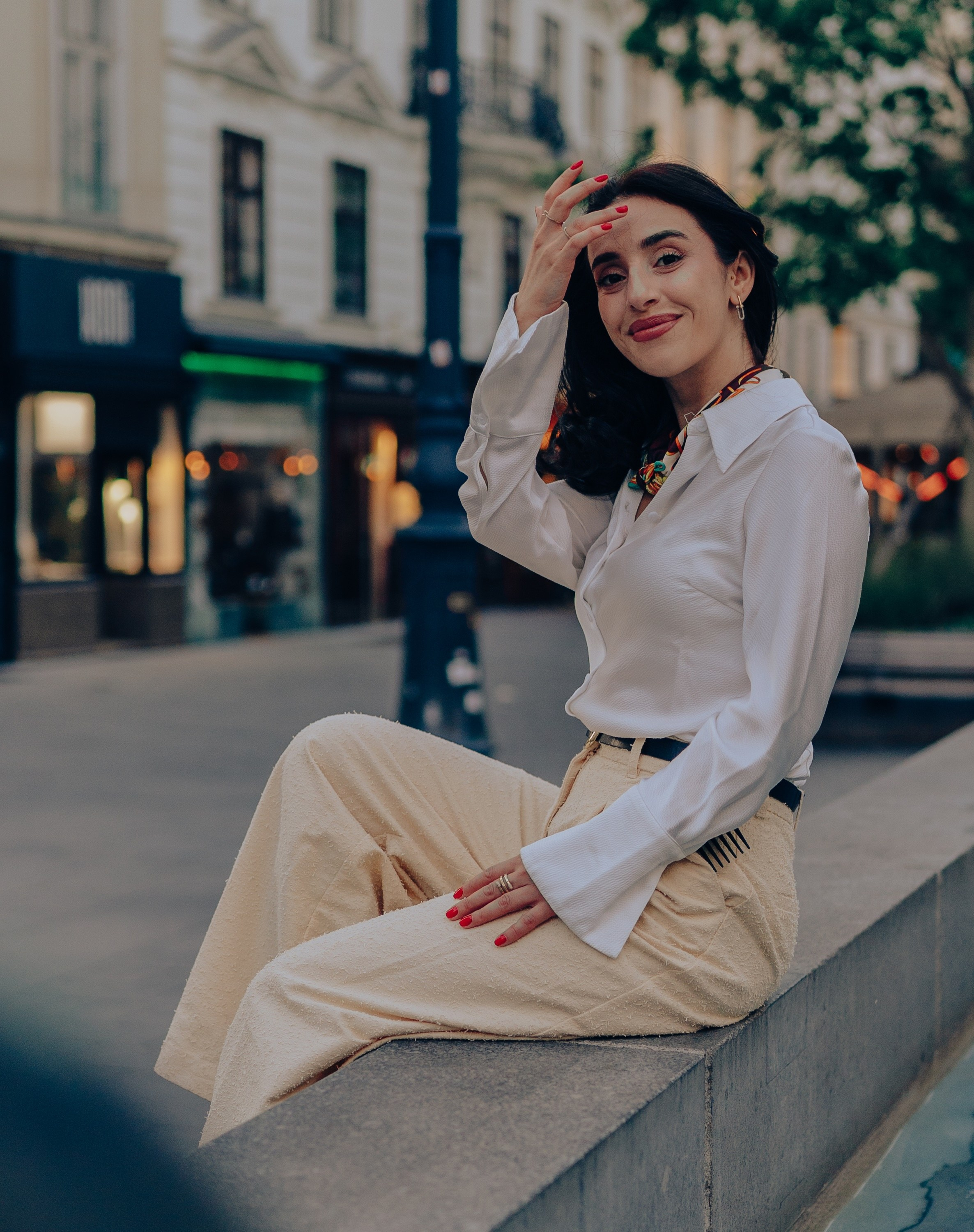 Woman sitting on the edge of a fountain in a Vienna square during a cinematic photoshoot