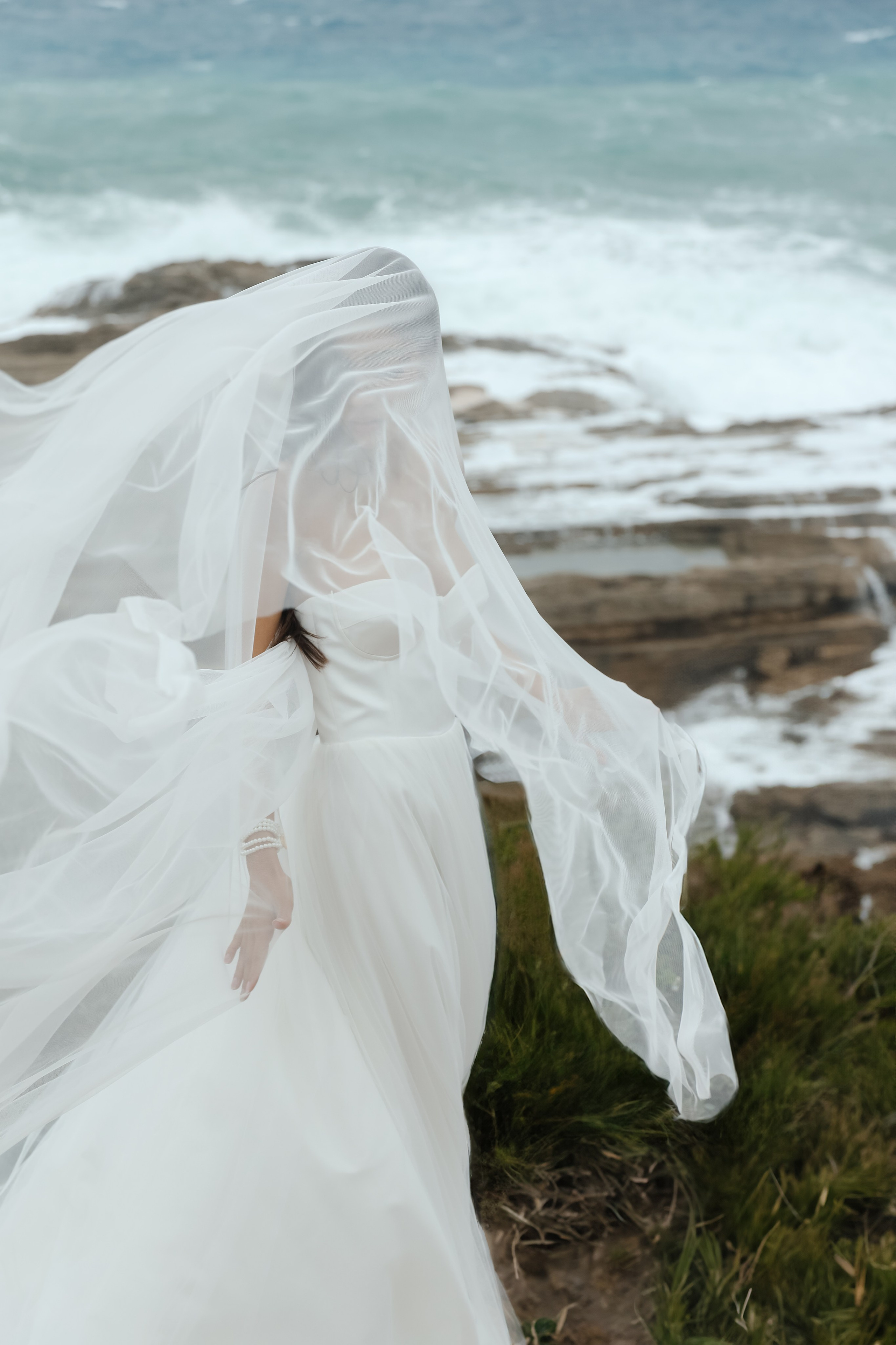 An art photo shoot of a girl in a wedding dress on the windy Kalithea beach in Rhodes, Greece
