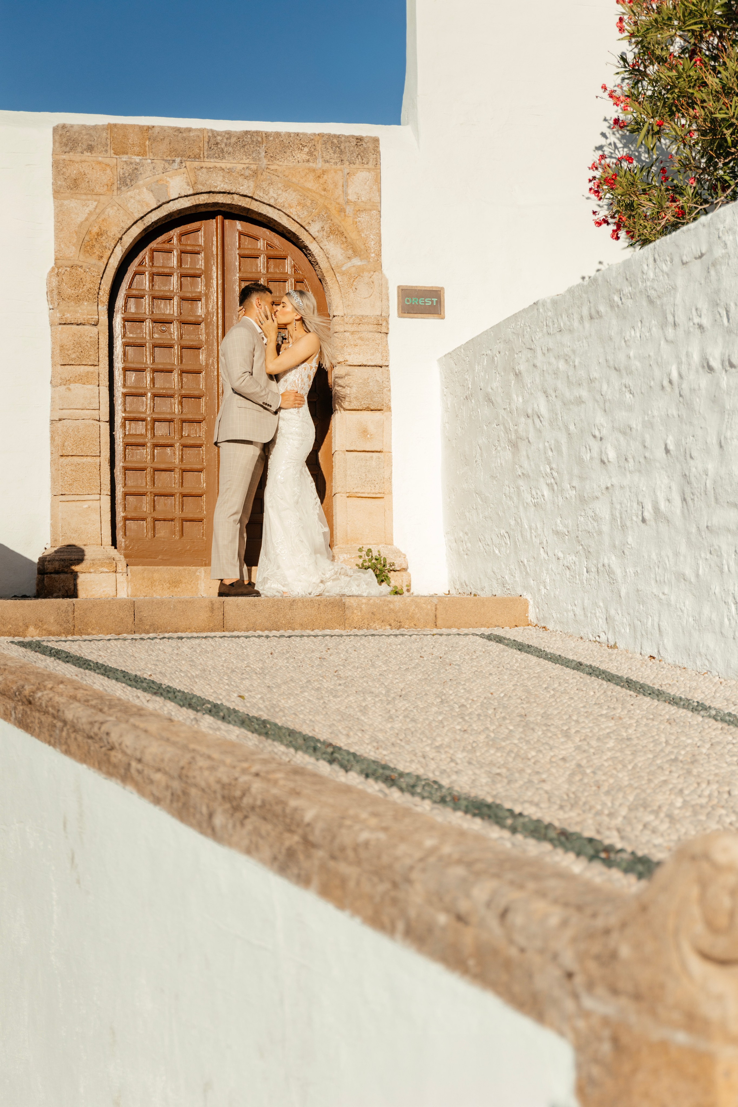 Bride and groom enjoying a quiet moment together on a cobblestone street in Lindos, with traditional Greek architecture around them