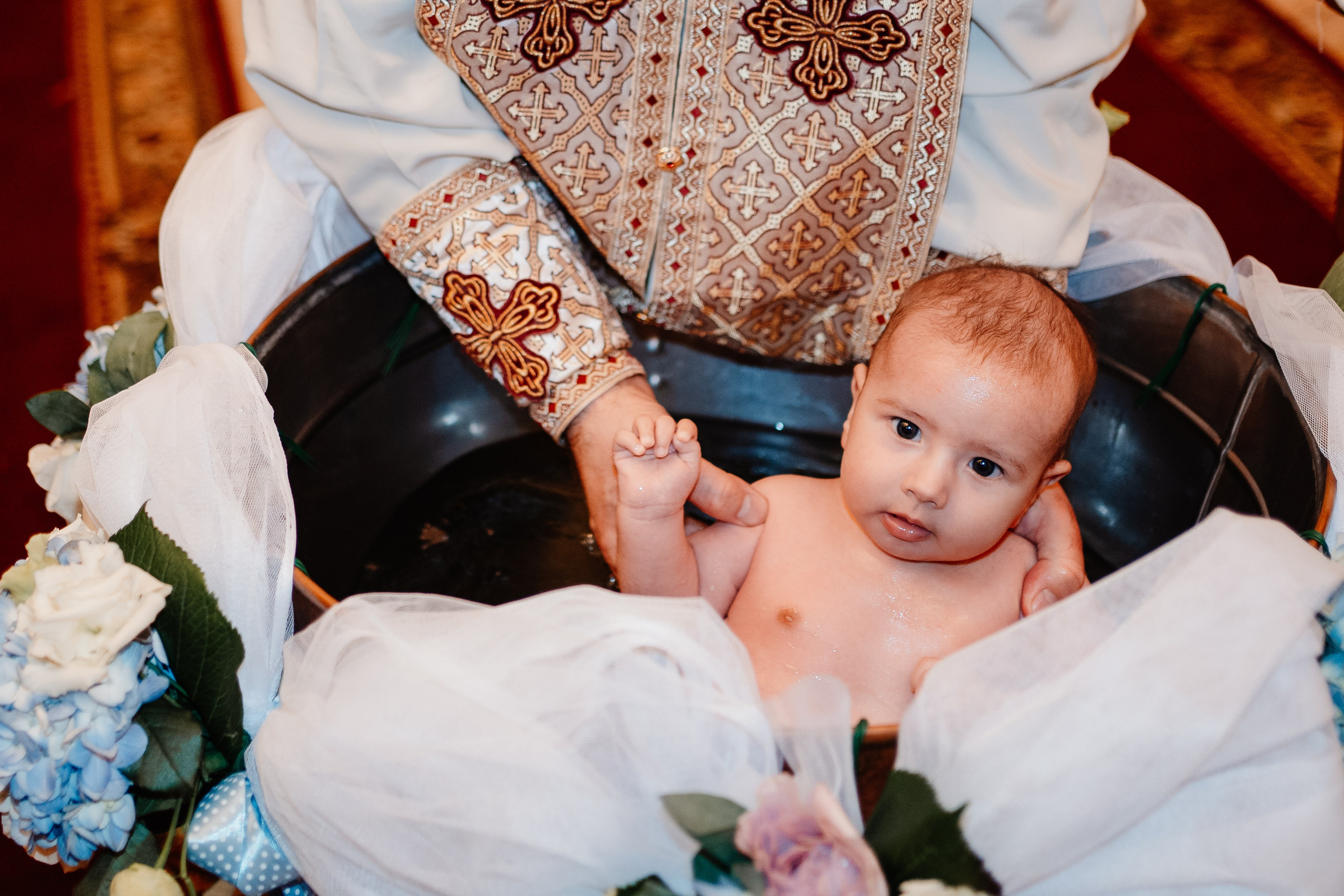 Instantaneu plin de tandrețe dintre părinți și bebeluș în ziua botezului, realizat în Bucuresti. Fotografie profesională de botez, capturând emoțiile autentice ale familiei într-un decor luminos și cald