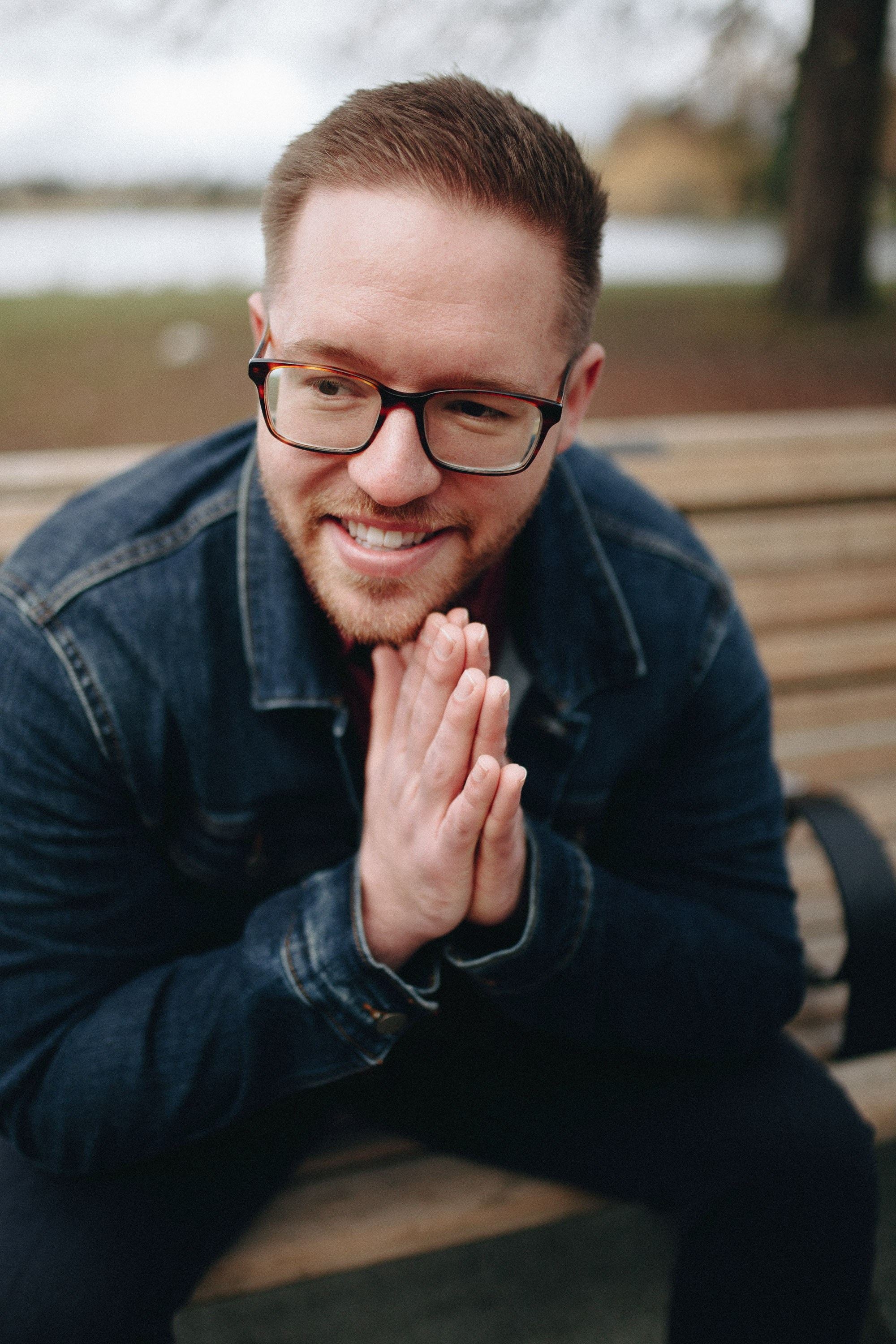Laughing man leaning forward, hands clasped