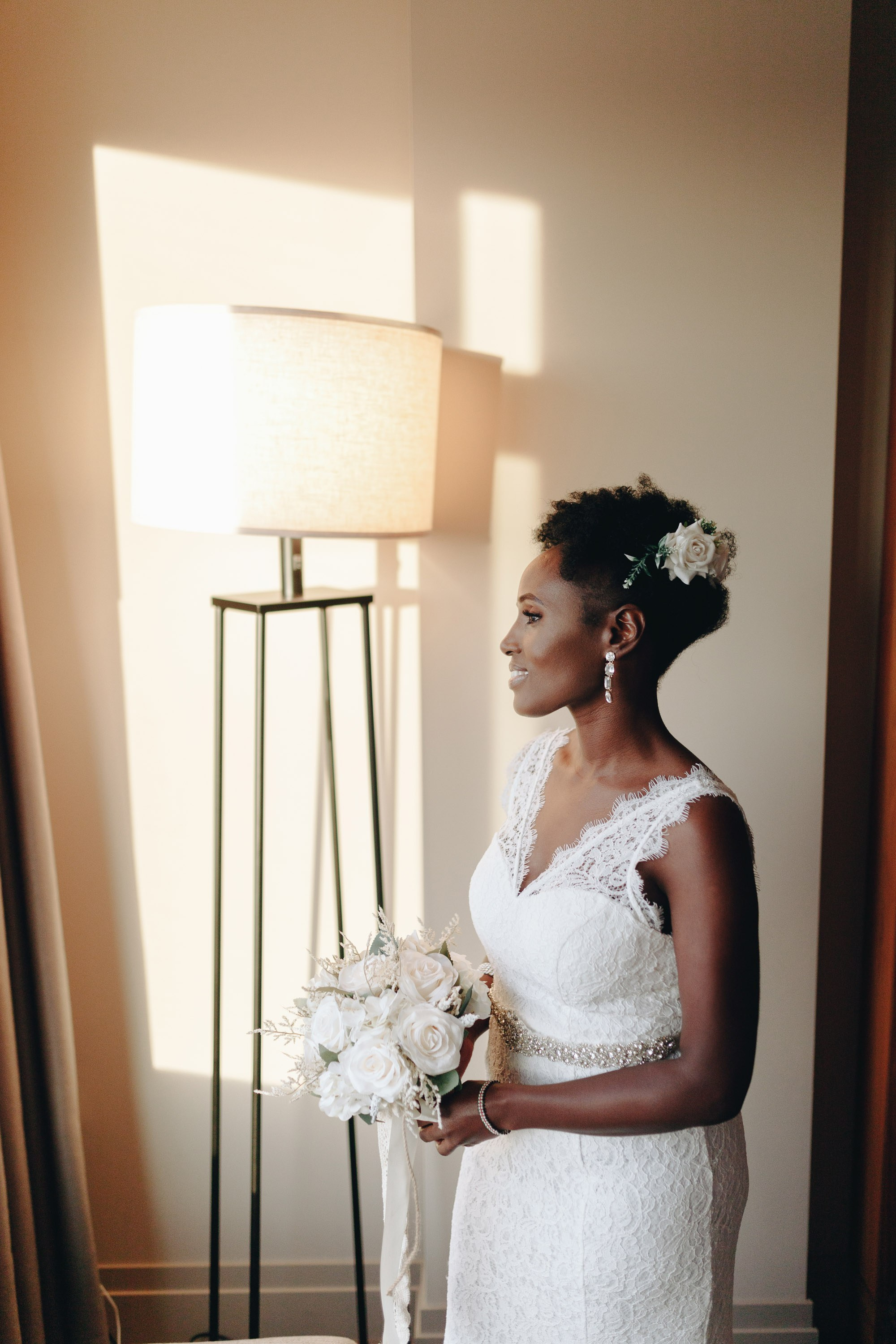 Bride standing by window in natural light, wedding preparation