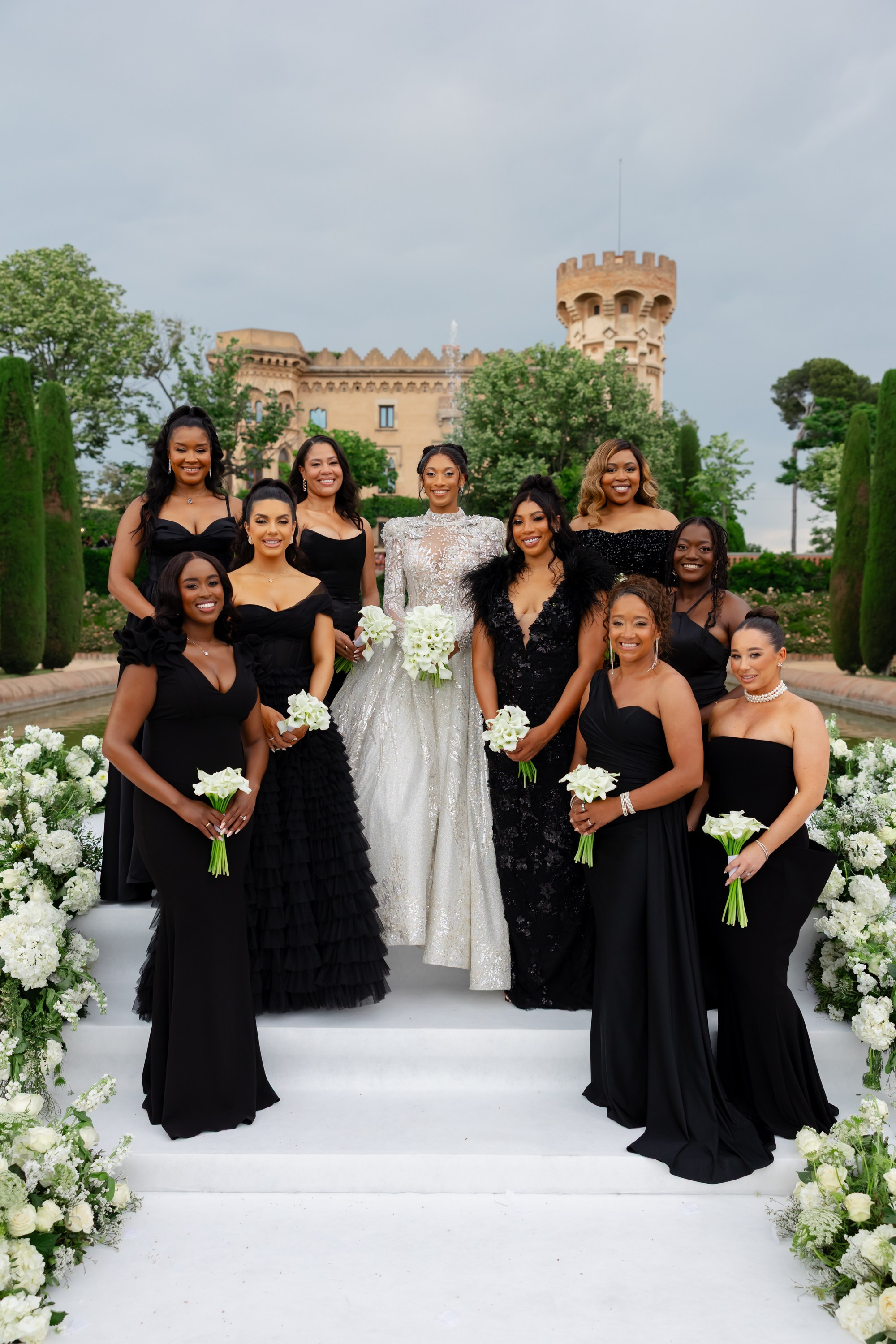 bride in a gorgeous wedding shiny dress posing with her bridesmaids in front of a castle in Spain