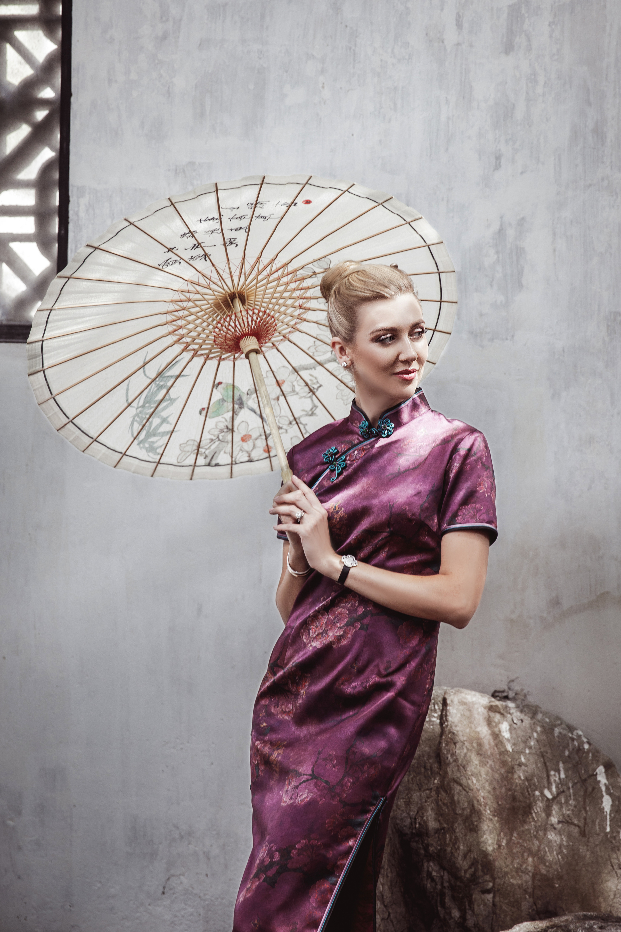 European-looking girl in Chinese traditional dress, holding a Chinese umbrella at YuGarden Chinese garden, Shanghai