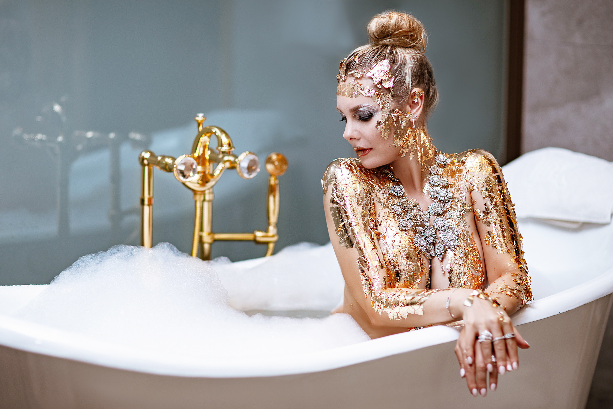 Photo session in a hotel room. Photographer Lola Pidluskaya. Girl in a bathtub with golden faucet, in soapy foam. girl covered with gold - unique makeup