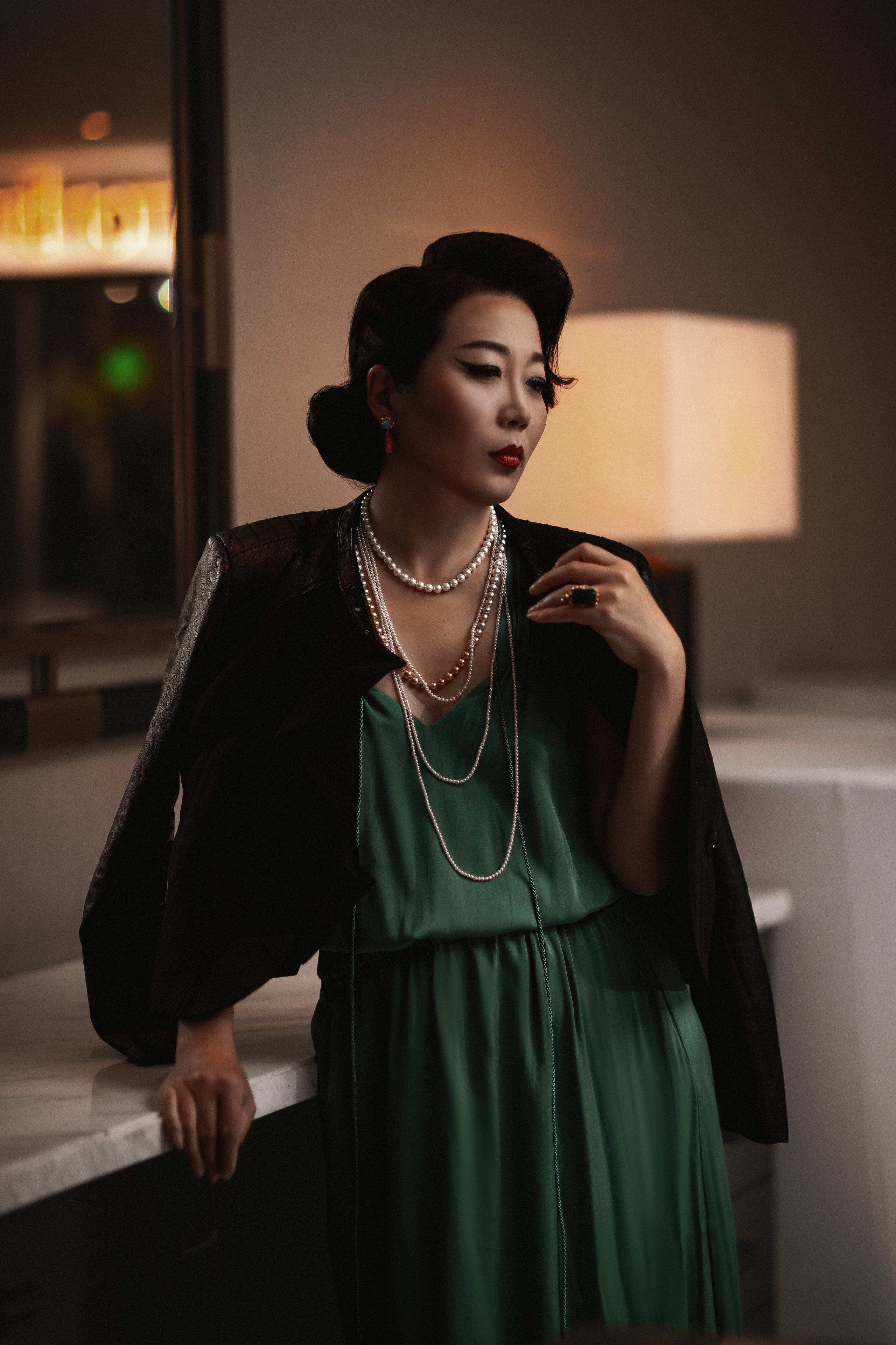 Elegant Chinese woman is a charming glamorous woman in retro style. Green dress and black jacket on her shoulders, soft light