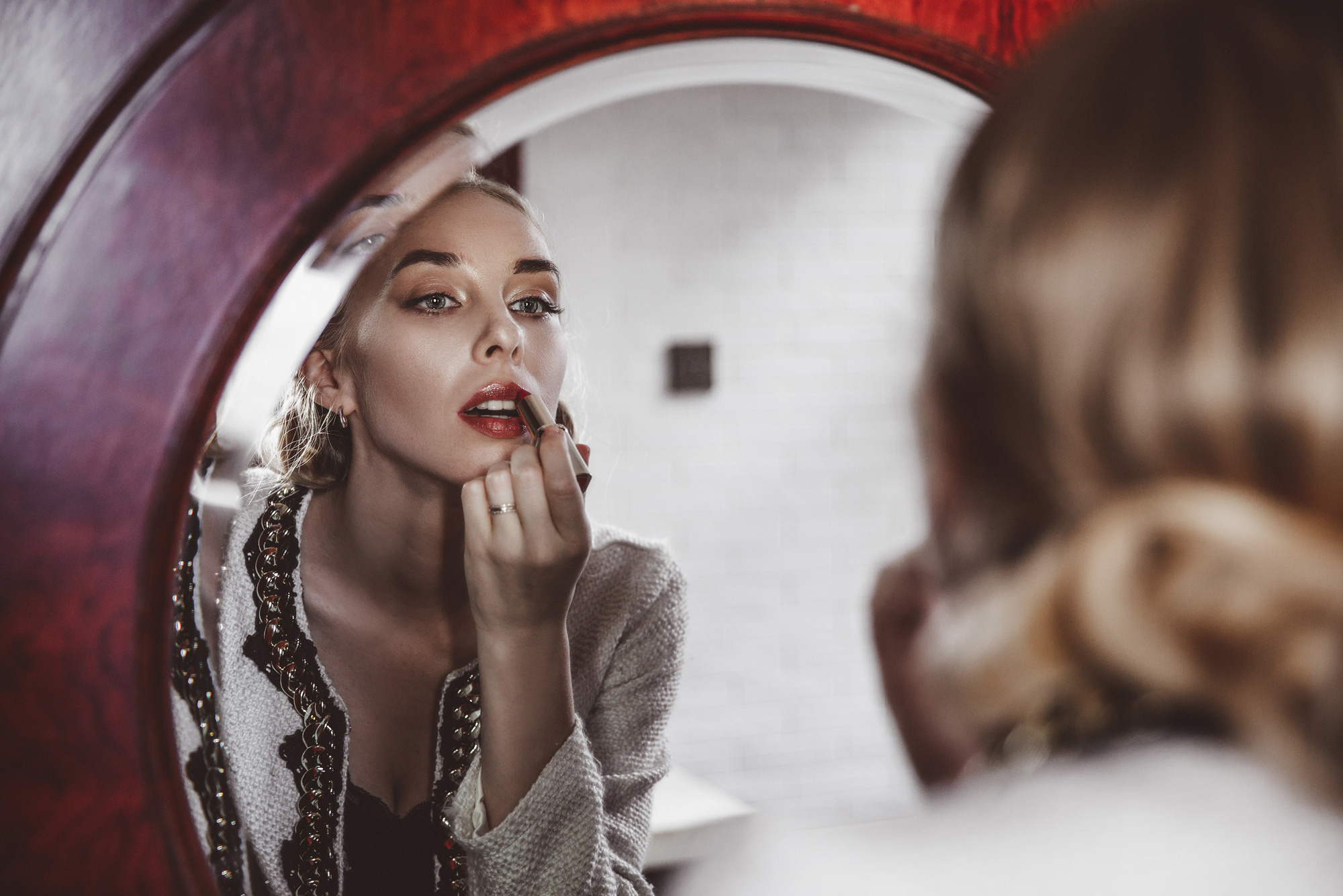 A girl paints her lips while looking in the mirror