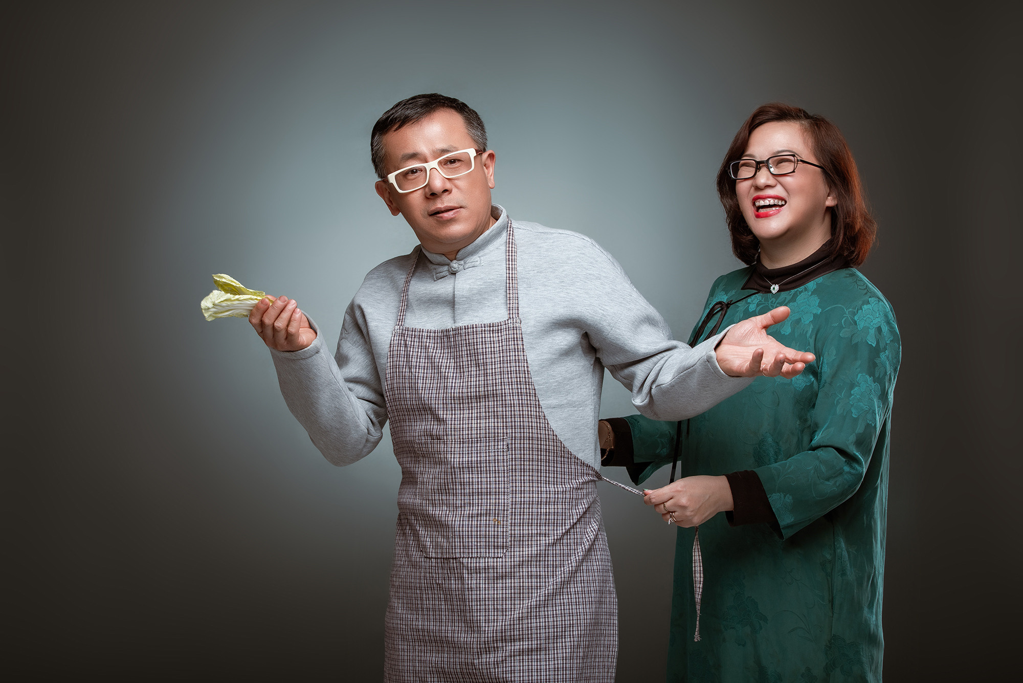 Humorous photography in studio for Chinese couple. Shanghai family is typical. The man is in the kitchen, the woman is the hostess