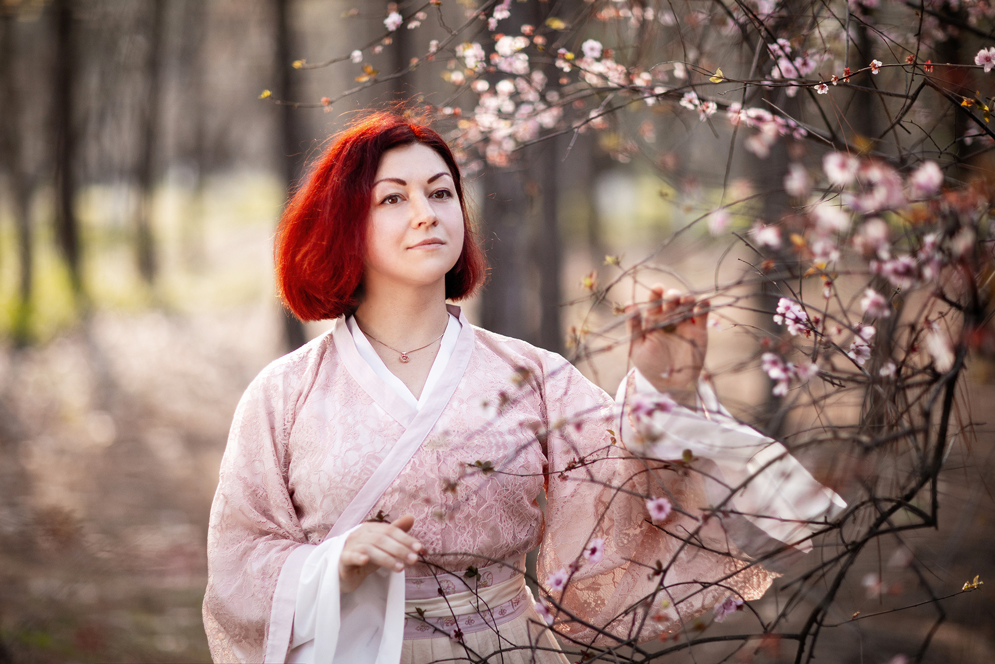 Spring photo shoot in Shanghai. Girl in Chinese traditional dress with blossoming pink sakura tree