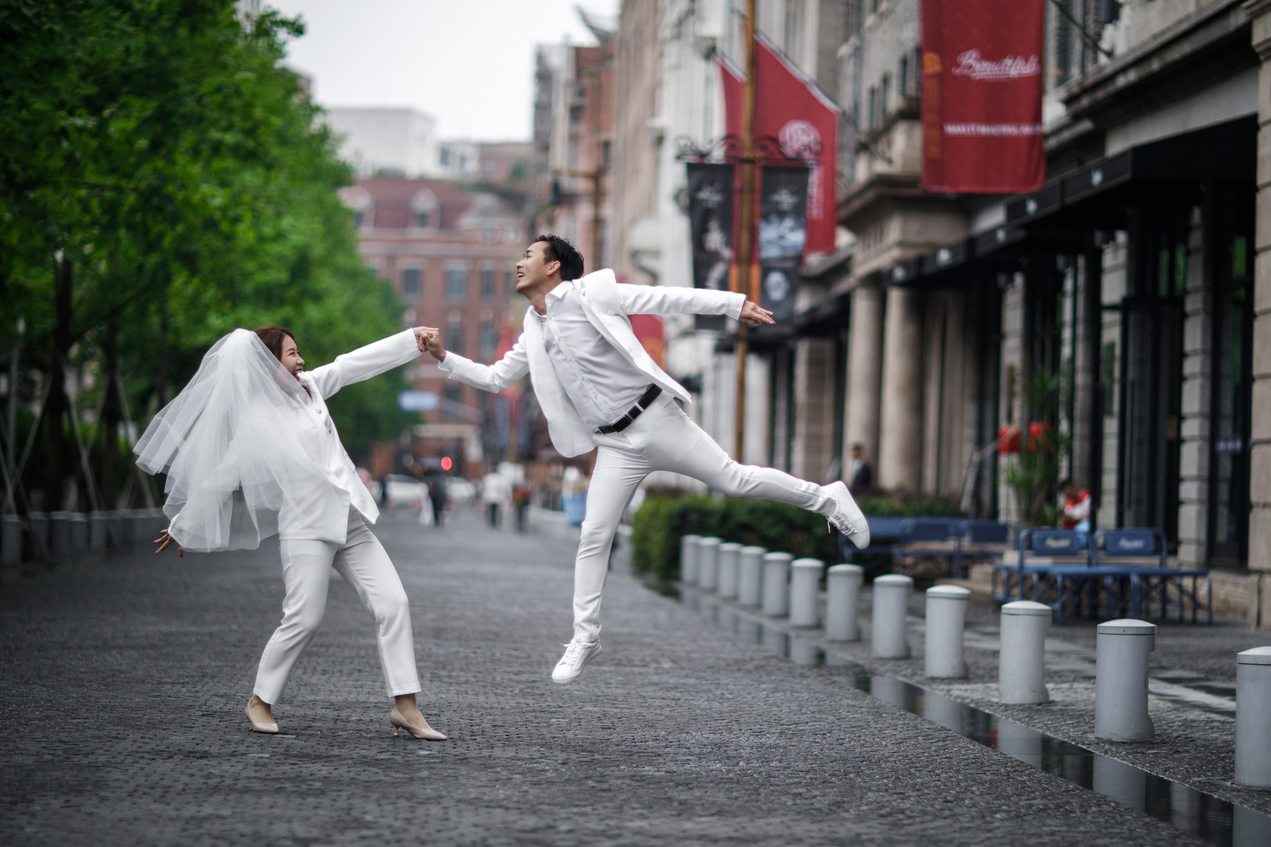 Original wedding photography for a couple from Indonesia. Bride in white pantsuit and veil. Shooting on the Bund, Shanghai. Photographer - Lola Pidluskaya