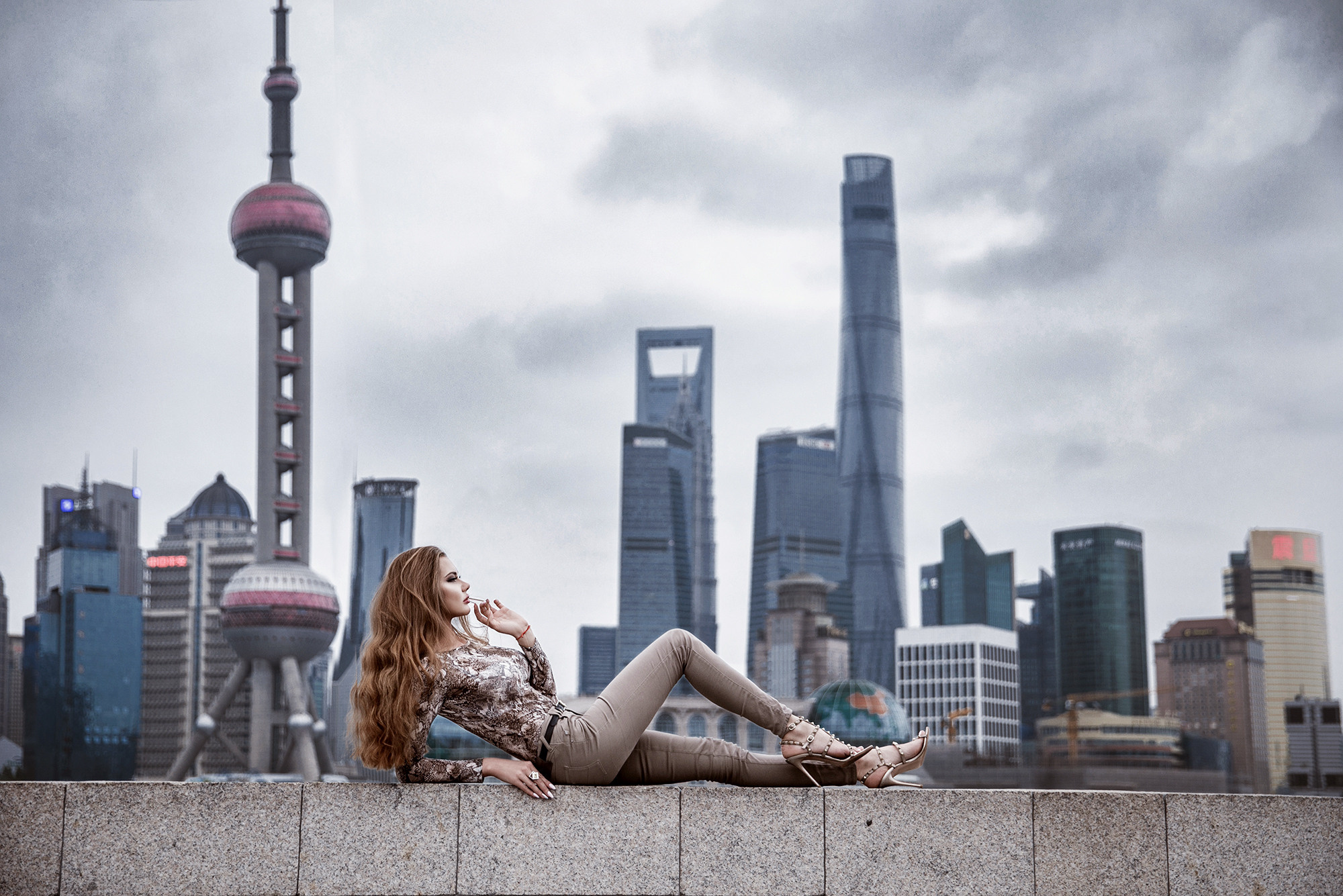 Charming girl on the background of Shanghai. Long-legged slender model with gorgeous long hair on Lujiazui background