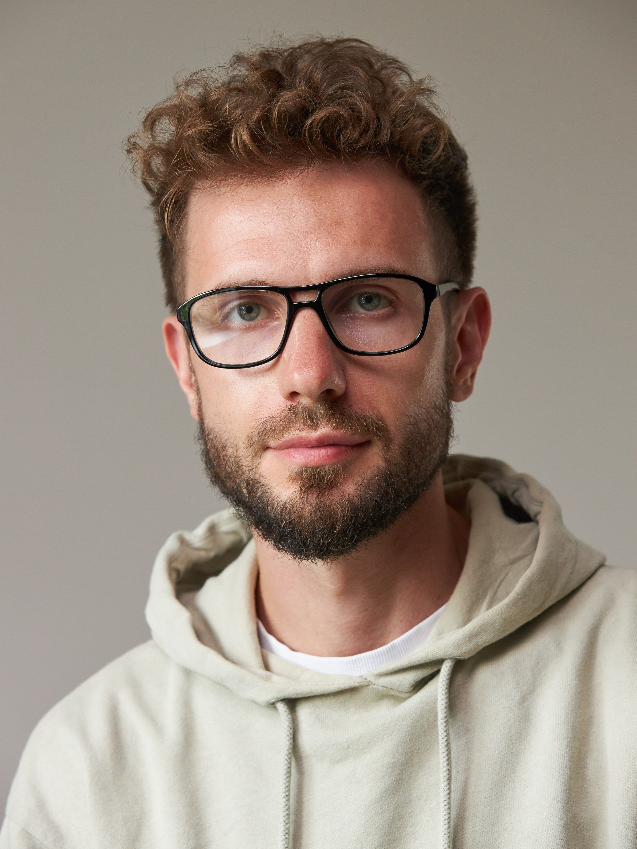 Eyewear model photoshoot - studio portrait of a young man on warm grey background - photographer Andrey Dunin