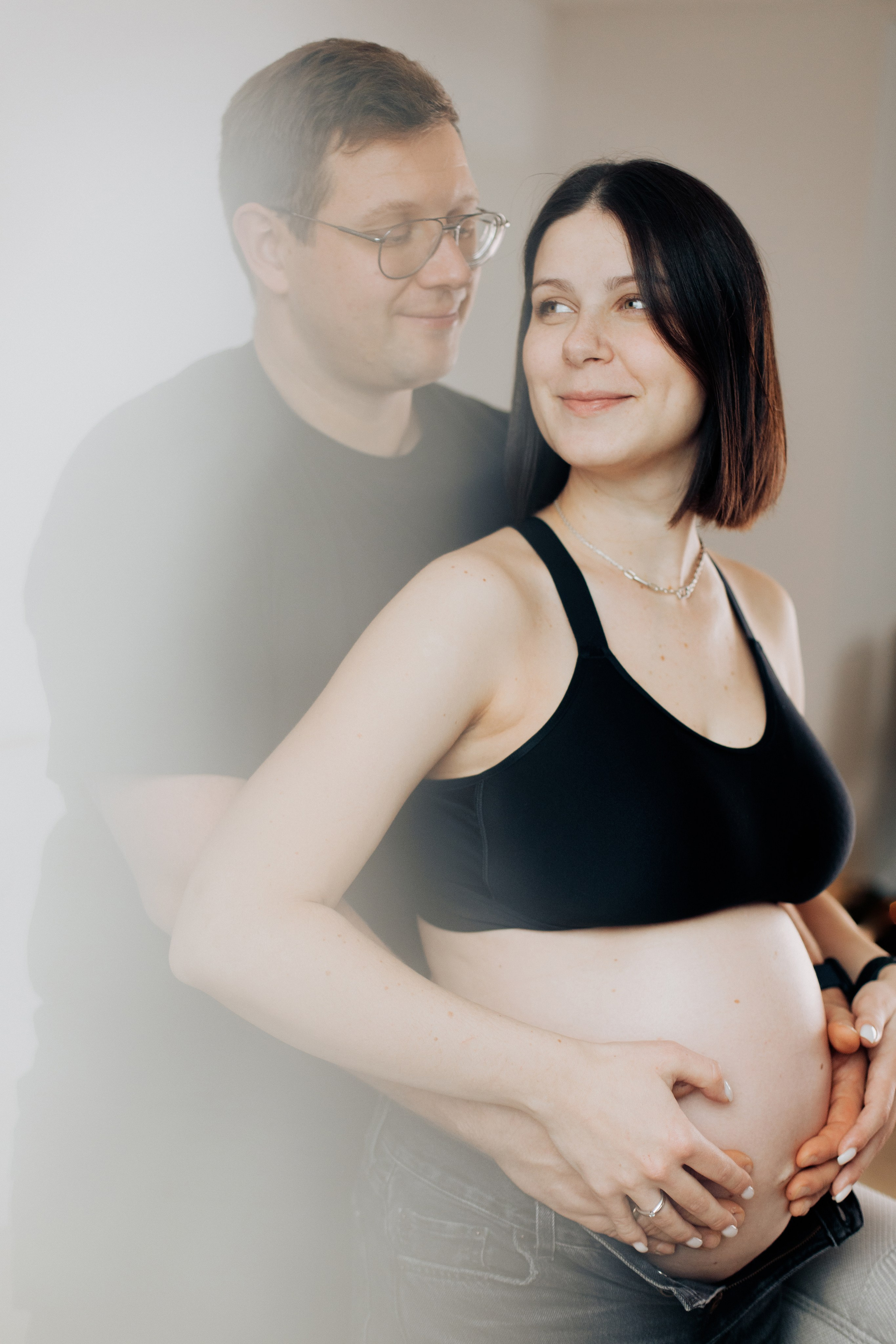 Mann umarmt seine schwangere Frau während eines Schwangerschaftsfotoshootings im Studio in Aschaffenburg.