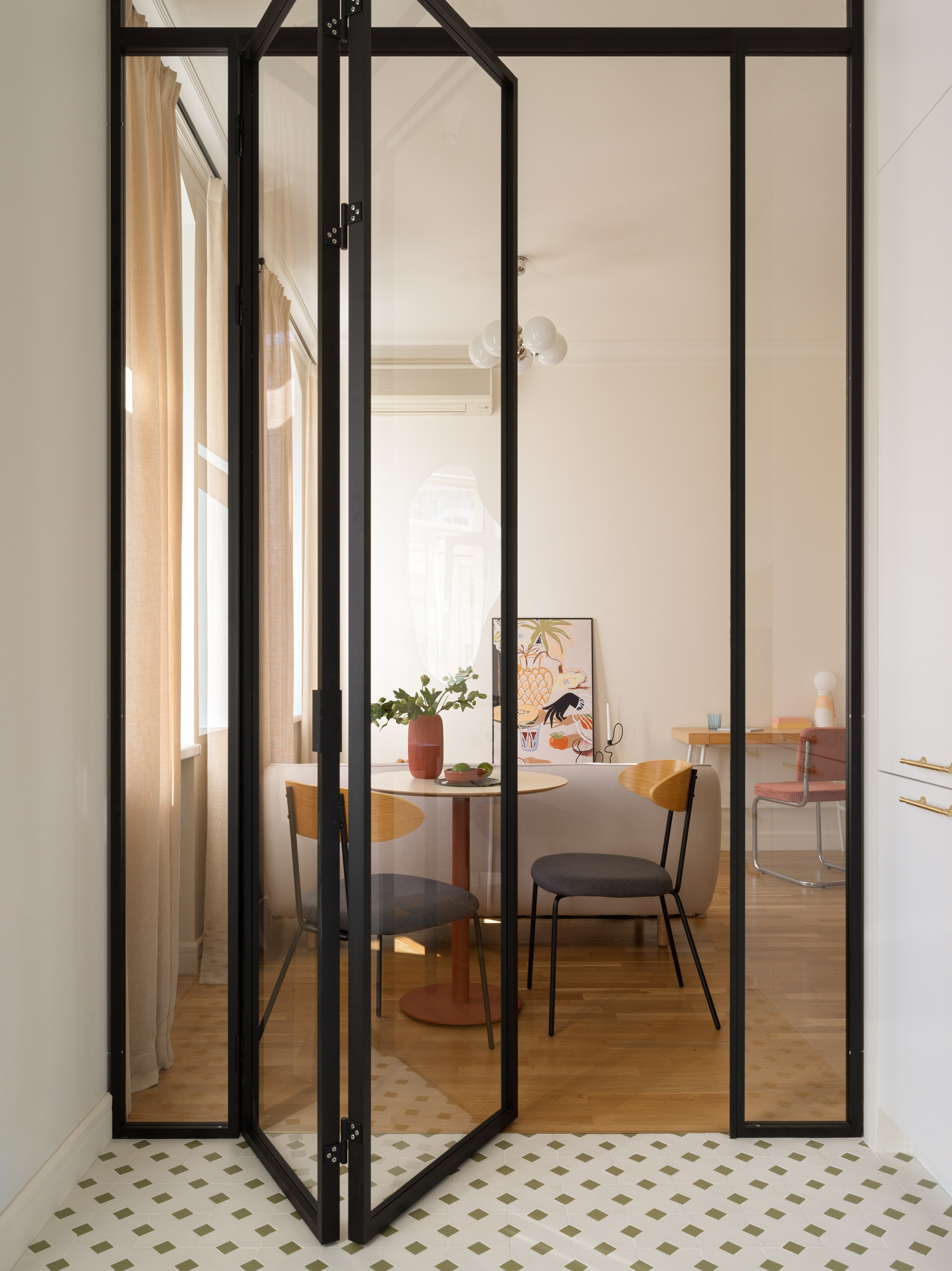 Перегородка из стекла в черном профиле, разделяющая кухню и гостиную.
