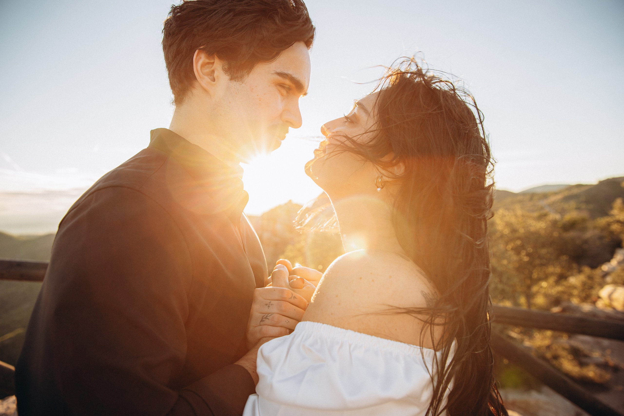 Bride and groom sharing a kiss with sun flare during a sunset elopement in the Spanish mountains in Barcelona. This intimate destination wedding portrait captures warmth, romance, and cinematic light.