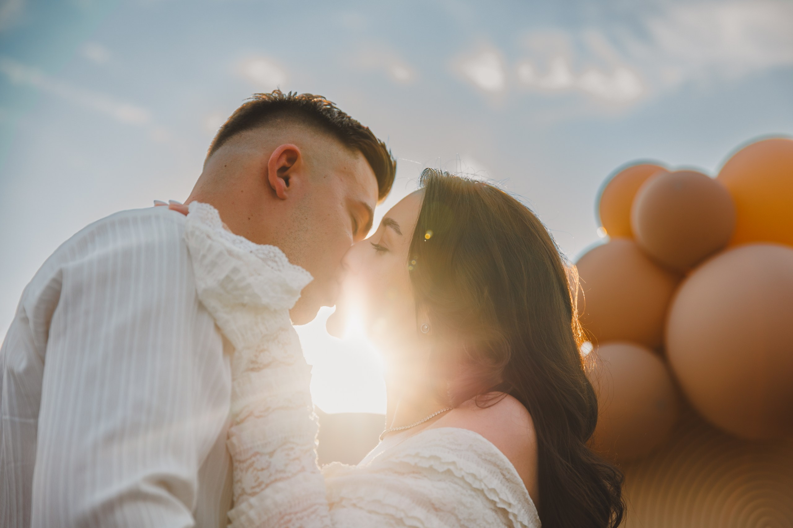 Sărut romantic cu flare de soare și baloane în fundal
