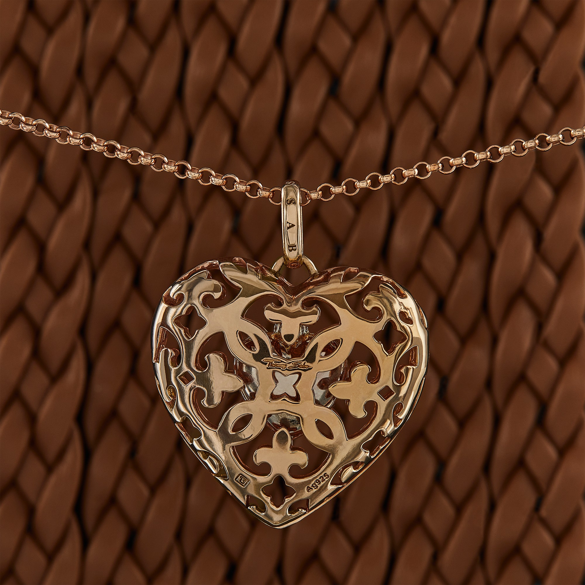 Photographer Roman Djuzev - Thomas Sabo's heart is made of pure silver with gilt on a background of pigtails made of leather, close-up.