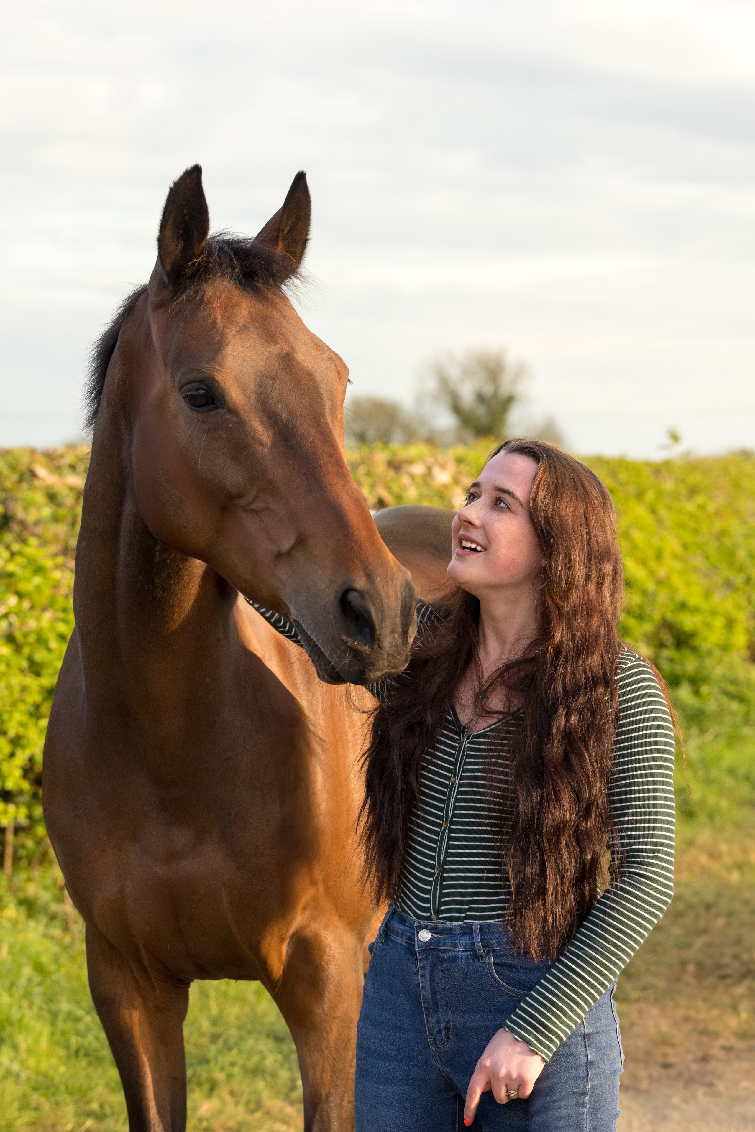 Natural interaction between teenage girl and her horse in open pasture
